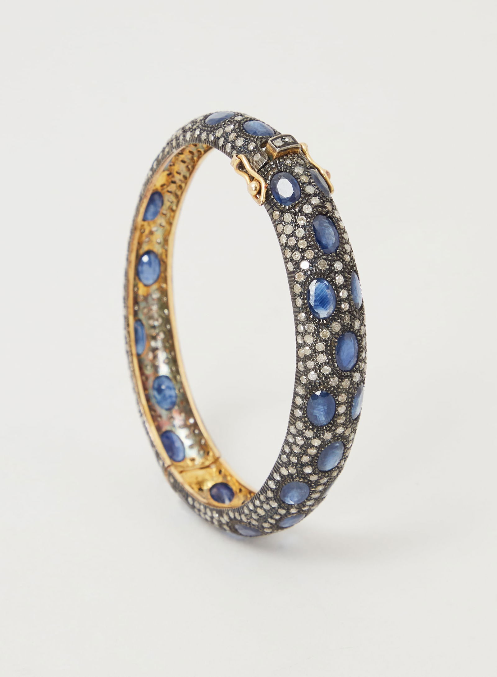 Gwyneth Paltrow | Sapphire and Diamond Bangle Bracelet: Sterling silver, 18k yellow gold, sapphire, and diamond bangle bracelet from the collection of Gwyneth Paltrow.In the Indian style, the hinged rigid bangle is fully decorated with circular-cut diamond