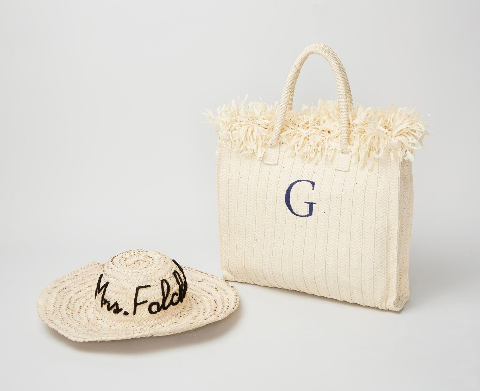 Gwyneth Paltrow | Mark & Graham Tote & Hat: A Mark & Graham raffia tote featuring an embroidered “G” at the front, paired with a poolside wide-brim sun hat woven from straw and customized with “Mrs. Falchuck” on the exte