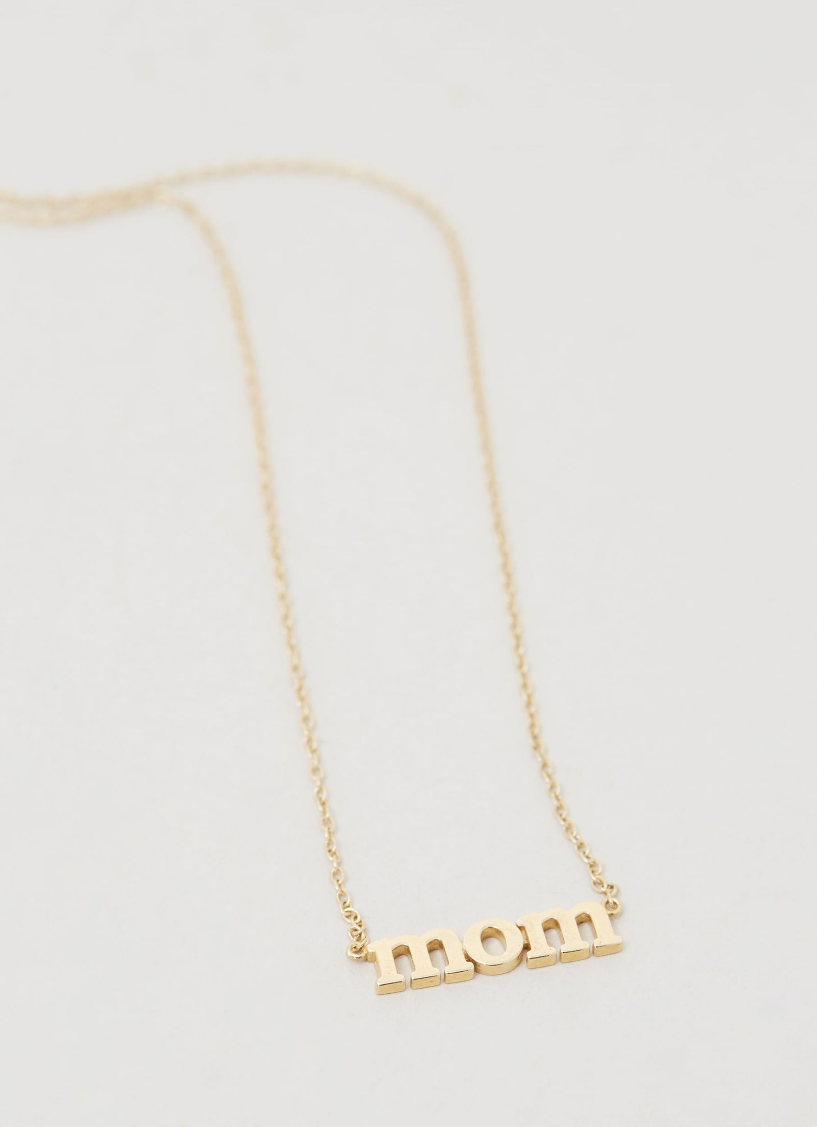 Gwyneth Paltrow | Jennifer Meyer 18k Yellow Gold MOM Pendant Necklace: An 18k yellow gold “MOM” pendant necklace designed by Jennifer Meyer from the collection of Gwyneth Paltrow.The necklace features a polished “mom” plaque suspended from a