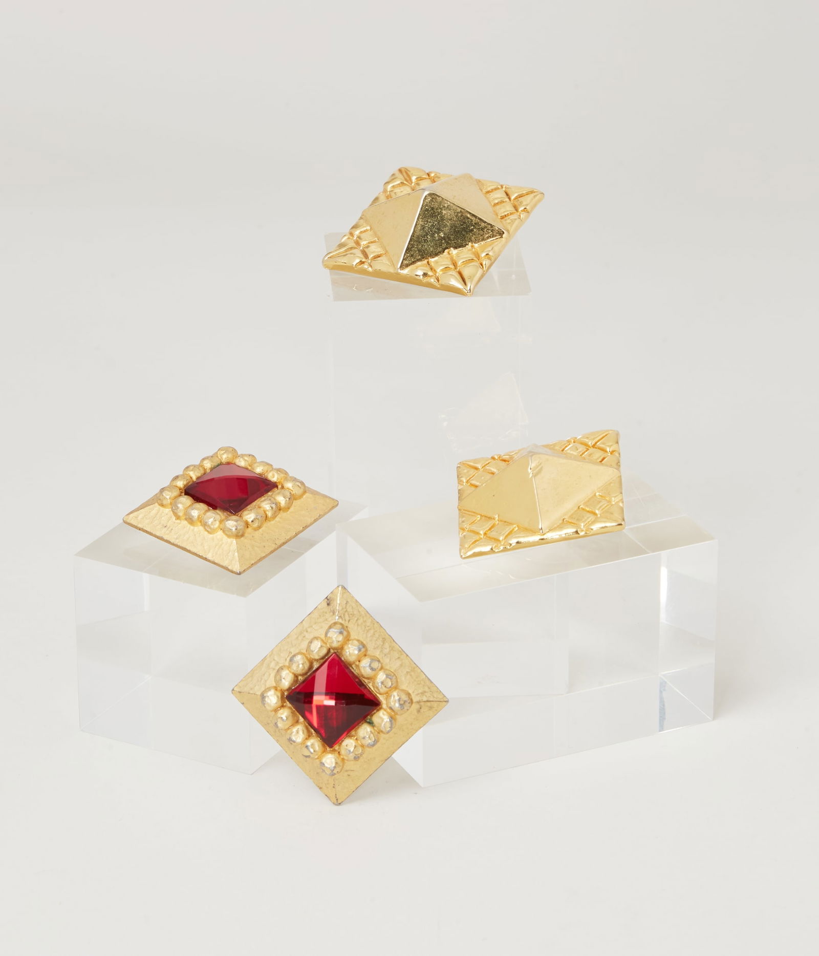 Givenchy | Two Pairs Of Clip-On Earrings : A grouping of two pairs of Givenchy clip-on earrings. Both earrings are gold-tone and a diamond shape; one pair is matte and features a facetted red stone at the center and the other is completely