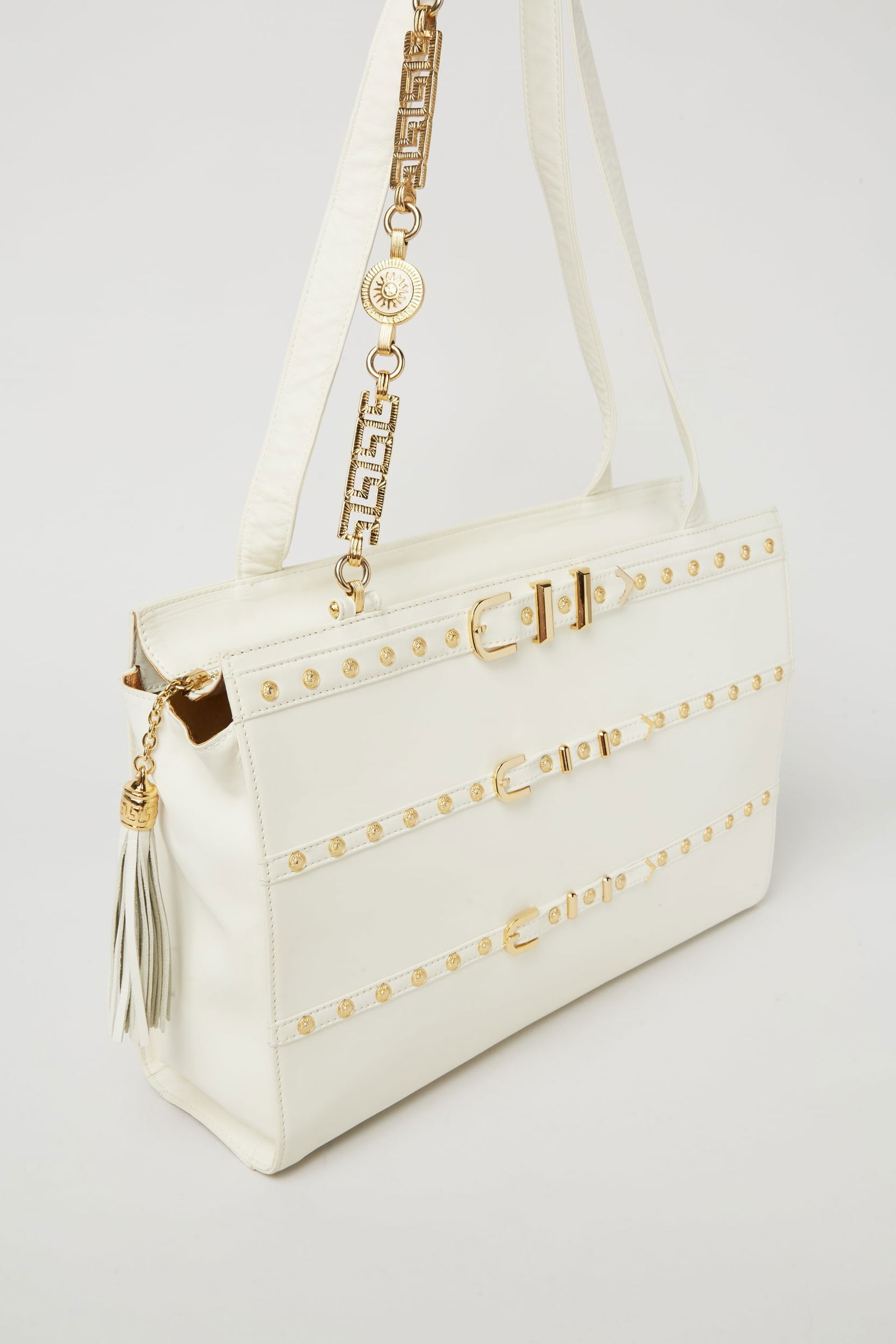 Gianni Versace | 1990s White Leather Tote: This a vintage 1990s Gianni Versace white leather tote with gold hardware. The box-shape bag has long top-handles with a significant strap drop.The front handle features gold tone hardware with Greek