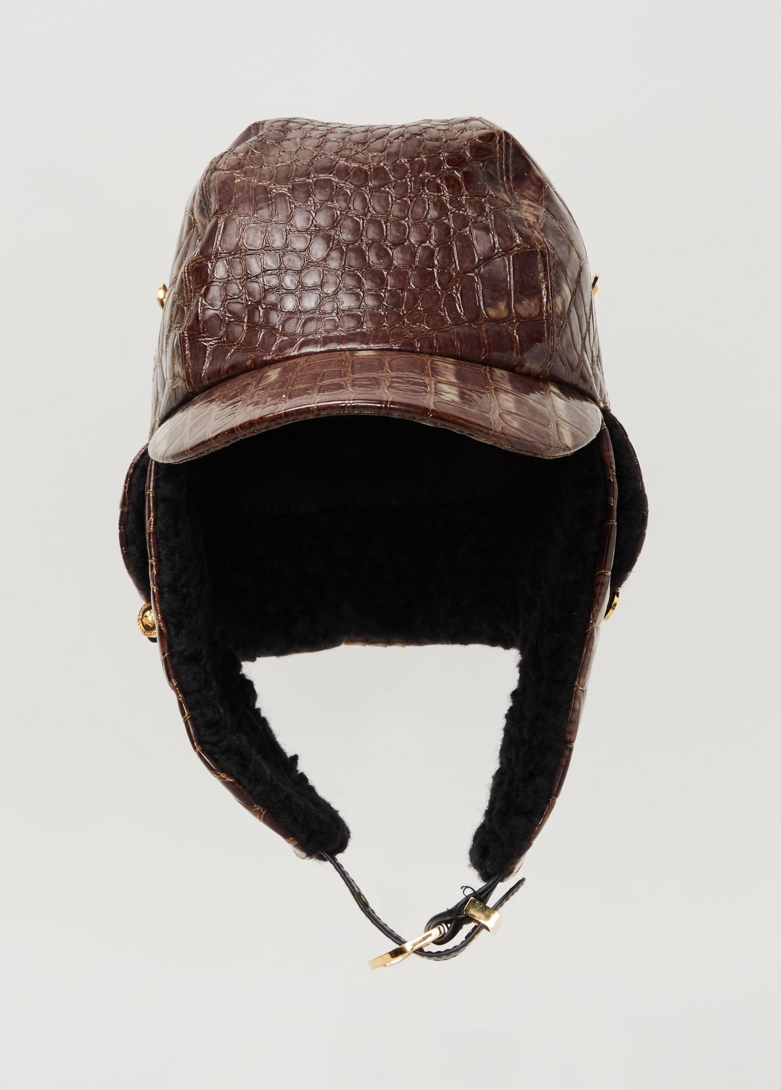 Gianni Versace | Croc-Embossed Aviator Cap: Gianni Versace high-gloss brown croc-embossed leather aviator cap.Featuring a paneled crown with topstitched seams and a curved extended brim. Integrated ear flaps with snap buttons extend from the