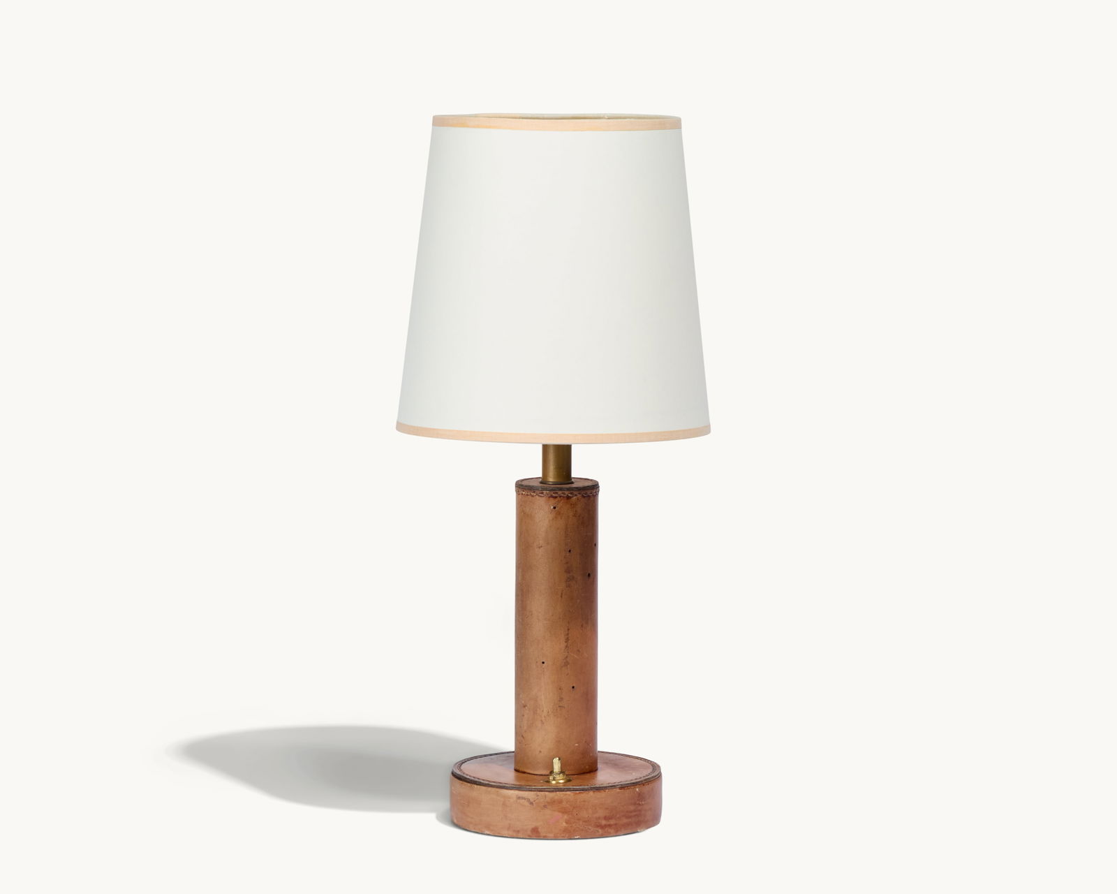 Gwyneth Paltrow | Table Lamp with Stitched Leather Base: A vintage table lamp with a round linen shade and a round leather stitched base.This article is from Gwyneth Paltrow’s former Brentwood home in Los Angeles, where she collaborated with interior