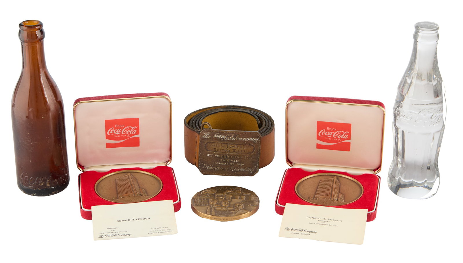 Jerry Weintraub | Group of Coca-Cola Collectibles: A group of Coca-Cola related collectibles including a modern Coca-Cola "fantasy" belt buckle, made to appear of age with leather belt; a 1986 first century commemorative medallion; a medal