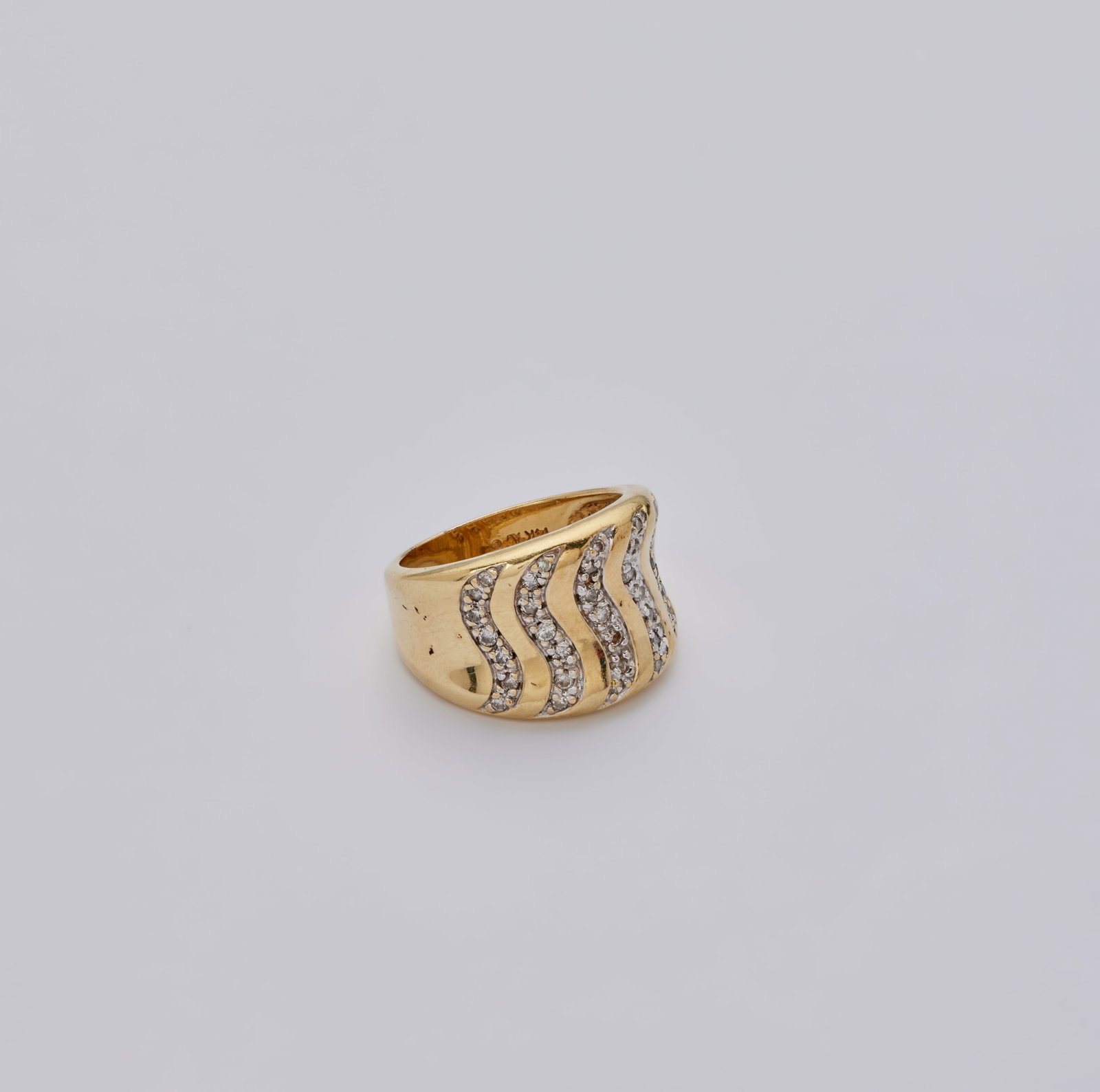Roberta Flack | 14K Yellow Gold and Diamond Ring: A 14k yellow gold and diamond ring, set to the top with a series of circular-cut diamond wavy lines, to the polished and tapering hoop, mounted in 14k yellow gold, 9.3 grams, ring size 7. Marked 14k. 