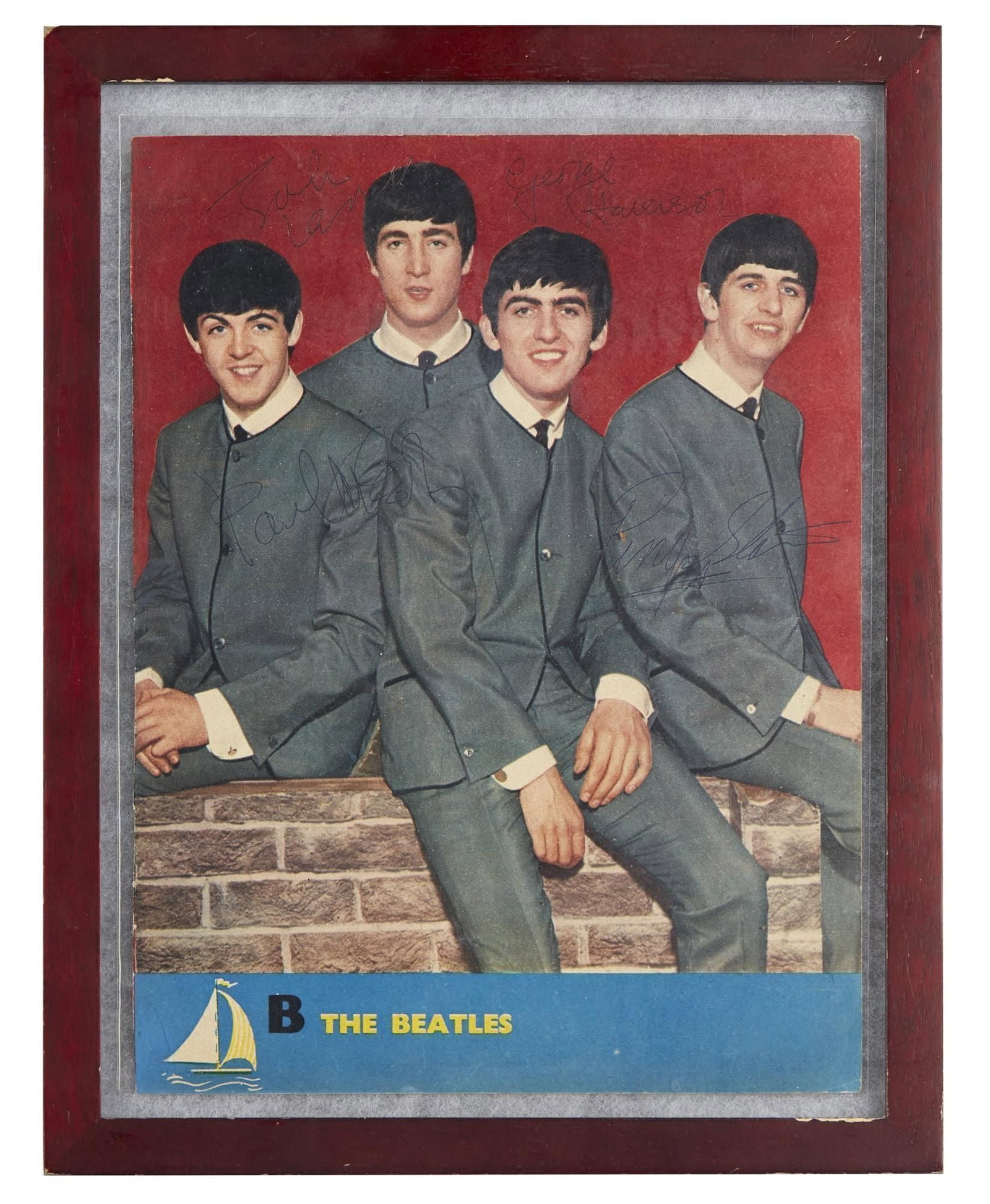 The Beatles | Band Double-Signed Magazine Page: A framed double-sided magazine photo of The Beatles signed by Paul John George and Ringo in blue ink to either side of the page (two signatures from each Beatle). Housed in a wooden frame box. Accompa