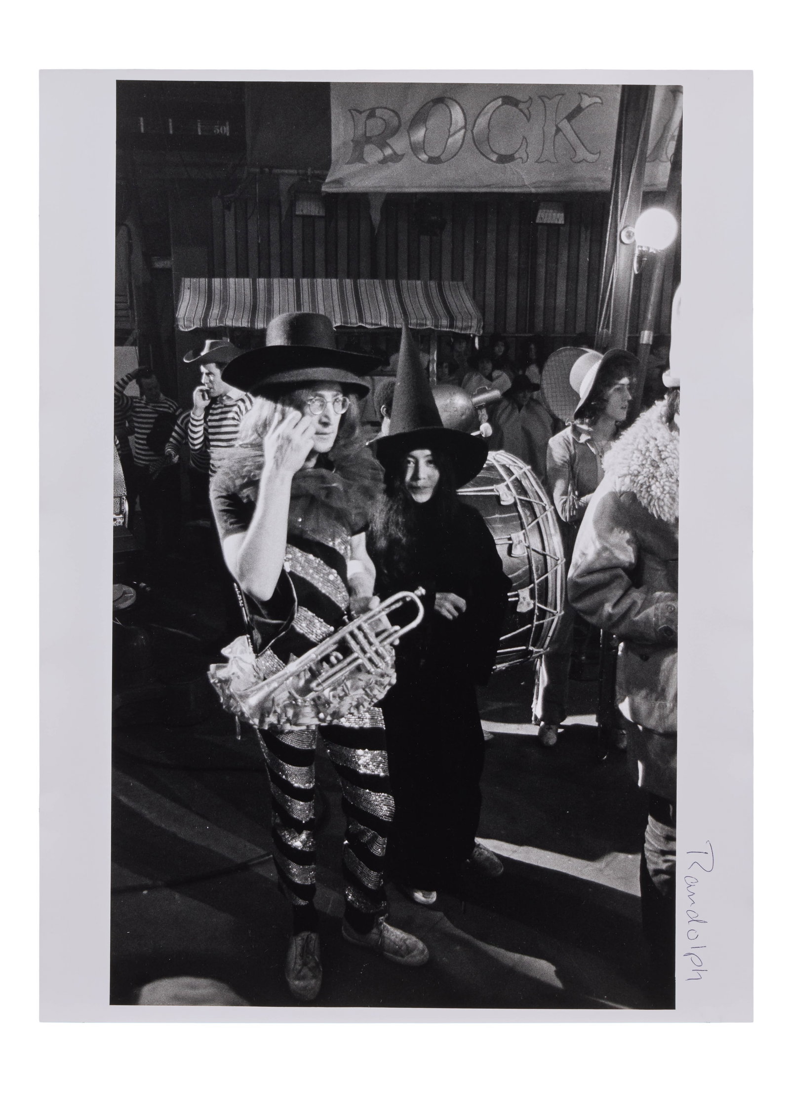 John Lennon | Mike Randolph Signed and Stamped Photo of John Lennon and Yoko Ono at Rock N Roll: A black and white photograph taken by Mike Randolph of John Lennon performing with The Dirty Mac at the Rock n Roll Circus at Intertel Television Studios in London on December 11th, 1968. The photo is