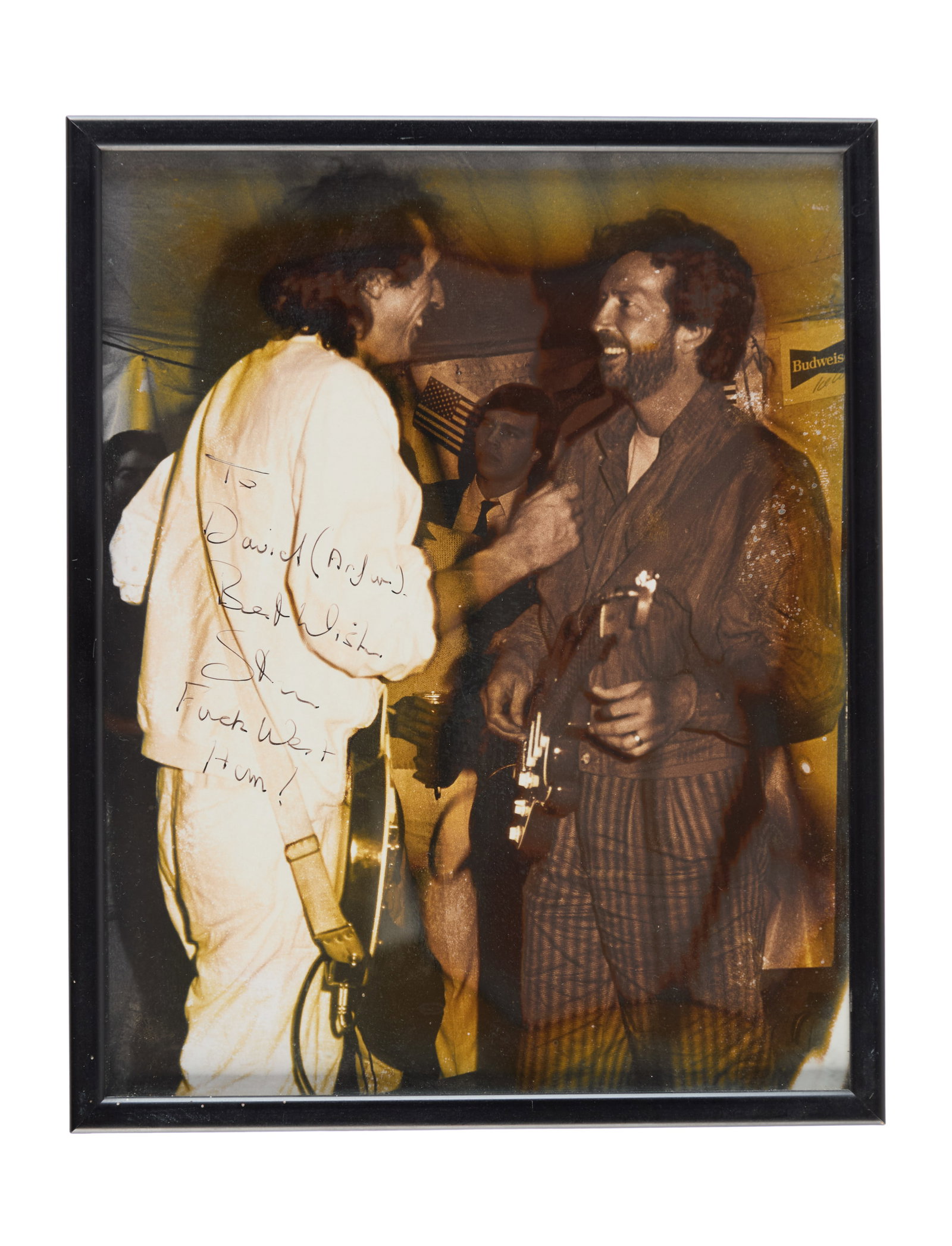 Eric Clapton | Photo Inscribed to David English: A framed photograph of Eric Clapton with David English, inscribed with a football (soccer) joke to English in black marker. The inscription reads: "To David 'Arfur' Best Wishes, Stan, F*CK West Ham". 