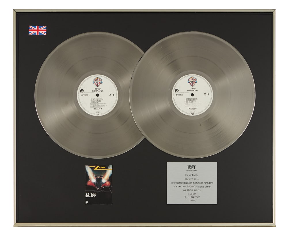 ZZ Top | Dusty Hill BPI-Certified "Multi-Platinum" British Sales Award for "Eliminator": A BPI-Certified "Multi-Platinum" Sales Award presented to Dusty Hill in 1984, to commemorate the sale of over 600,000 units in the UK of ZZ Top's 1983 studio album Eliminator. Released on March 23, 19