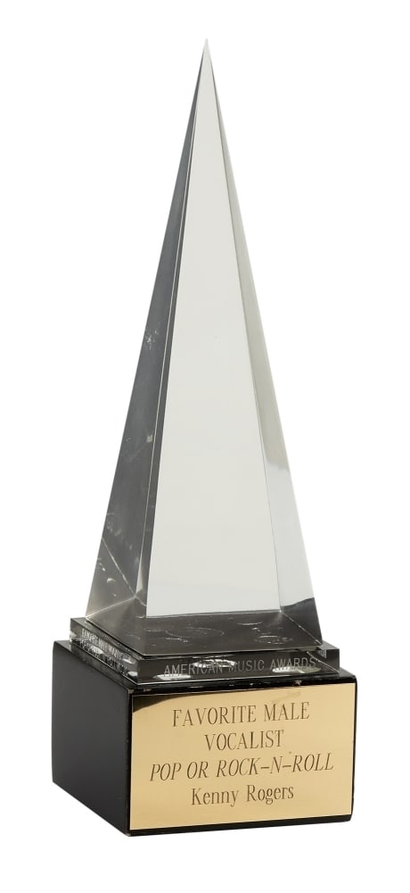 Kenny Rogers | 1981 "Favorite Male Vocalist" AMA Award: An American Music Award presented to Kenny Rogers for "Favorite Male Vocalist Pop or Rock N Roll" in 1981. The award sits on a wooden base with a gold-tone plaque. The top of the award is an acrylic p
