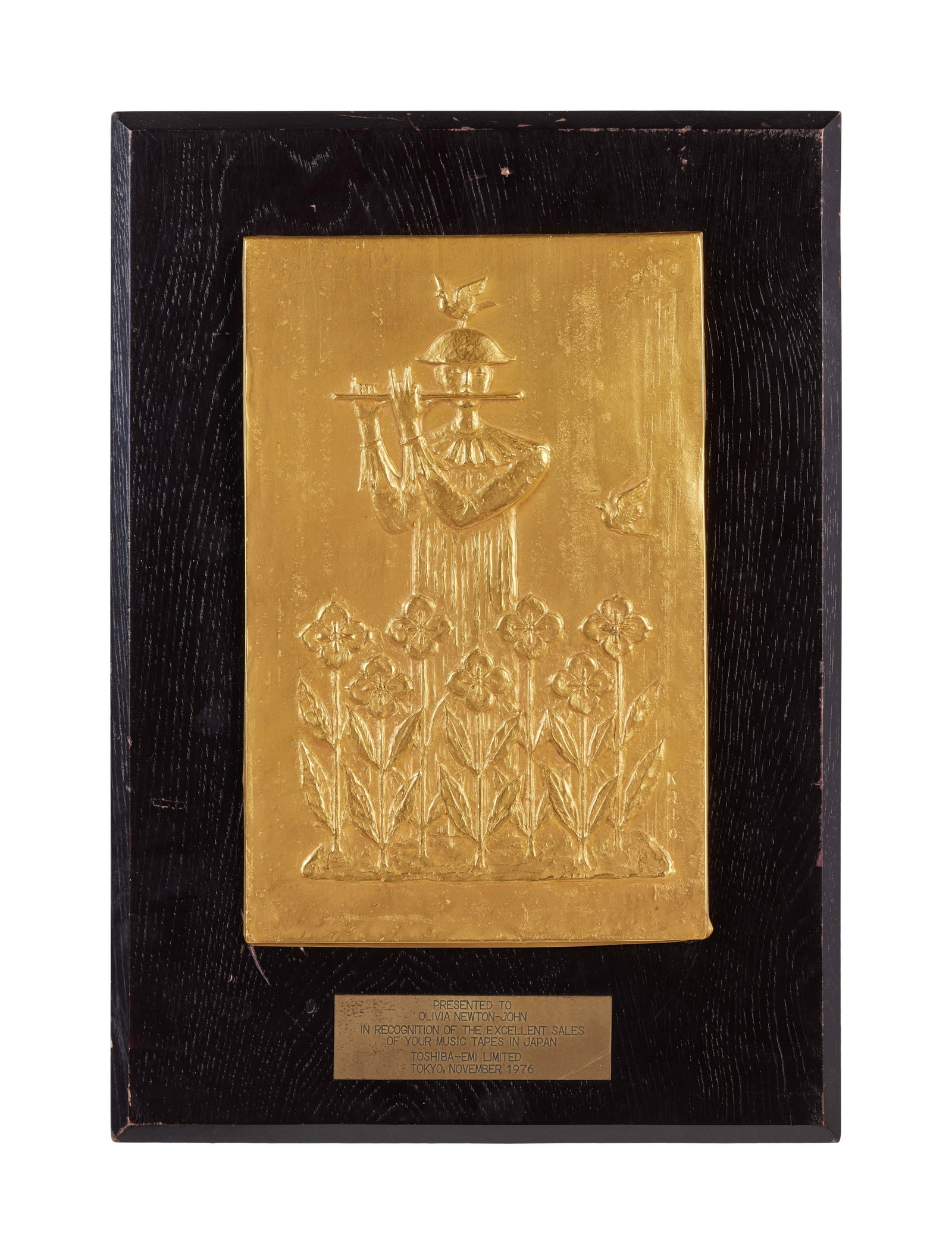 Olivia Newton-John | 1976 Japanese Cassette Sales Award with Transparency: A plaque presented to Olivia Newton-John by Toshiba-EMI in November, 1976, in recognition of her tape sales in Japan. Together with a transparency of Olivia holding the plaque.