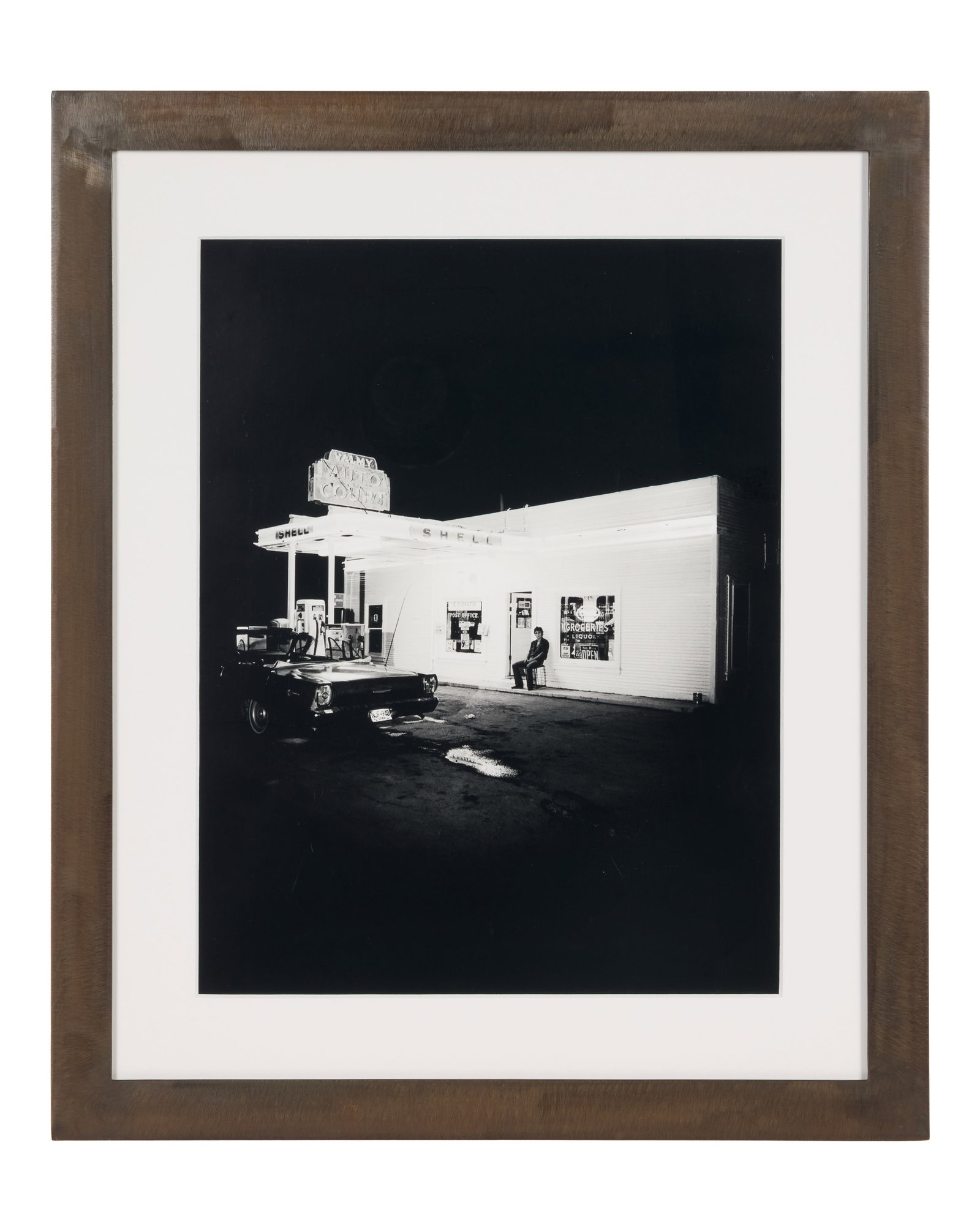 Bruce Springsteen | Eric Meola Vintage Darkness at the Edge of Town Photo Print: A framed black-and-white photo print of Bruce Springsteen sitting in front of a "Valmy Auto Court" gas station and store in Nevada, taken by photographer Eric Meola in 1977. Springsteen was on