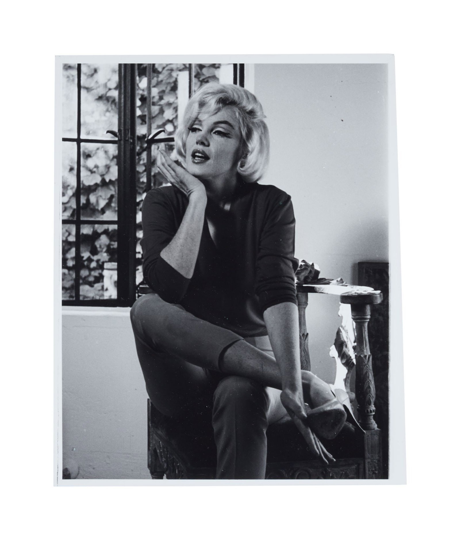 Marilyn Monroe | 1962/1990 Never-Published Black and White Photograph by Allan Grant: A 1990 later print hand-printed by Allan Grant; glossy finish weight-and-a-half paper depicting the star in mid-speech as she sits on a chair at her Fifth Helena Drive house in the Brentwood section
