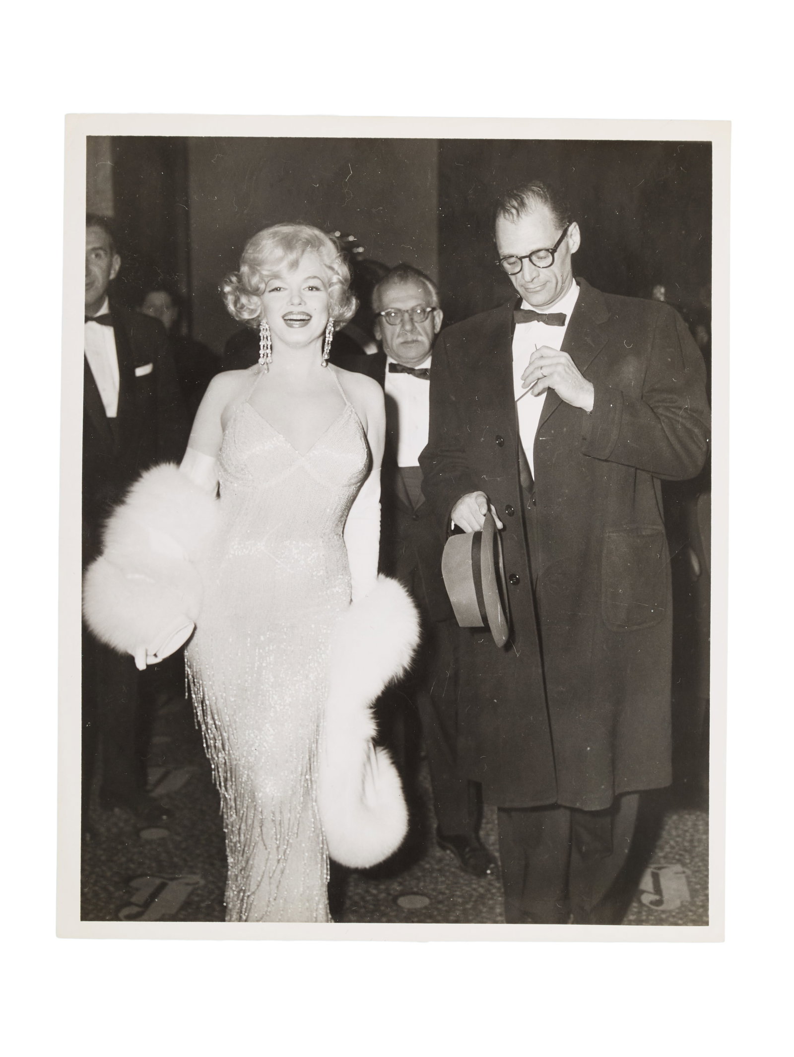 Marilyn Monroe | 1959 Arthur Miller-Related Black and White Photograph by Paul Schumach: An original print; glossy finish, depicting the star and then-husband at the premiere of her 1959 United Artists comedy "Some Like It Hot" which took place in New York City on March 29, 1959; verso