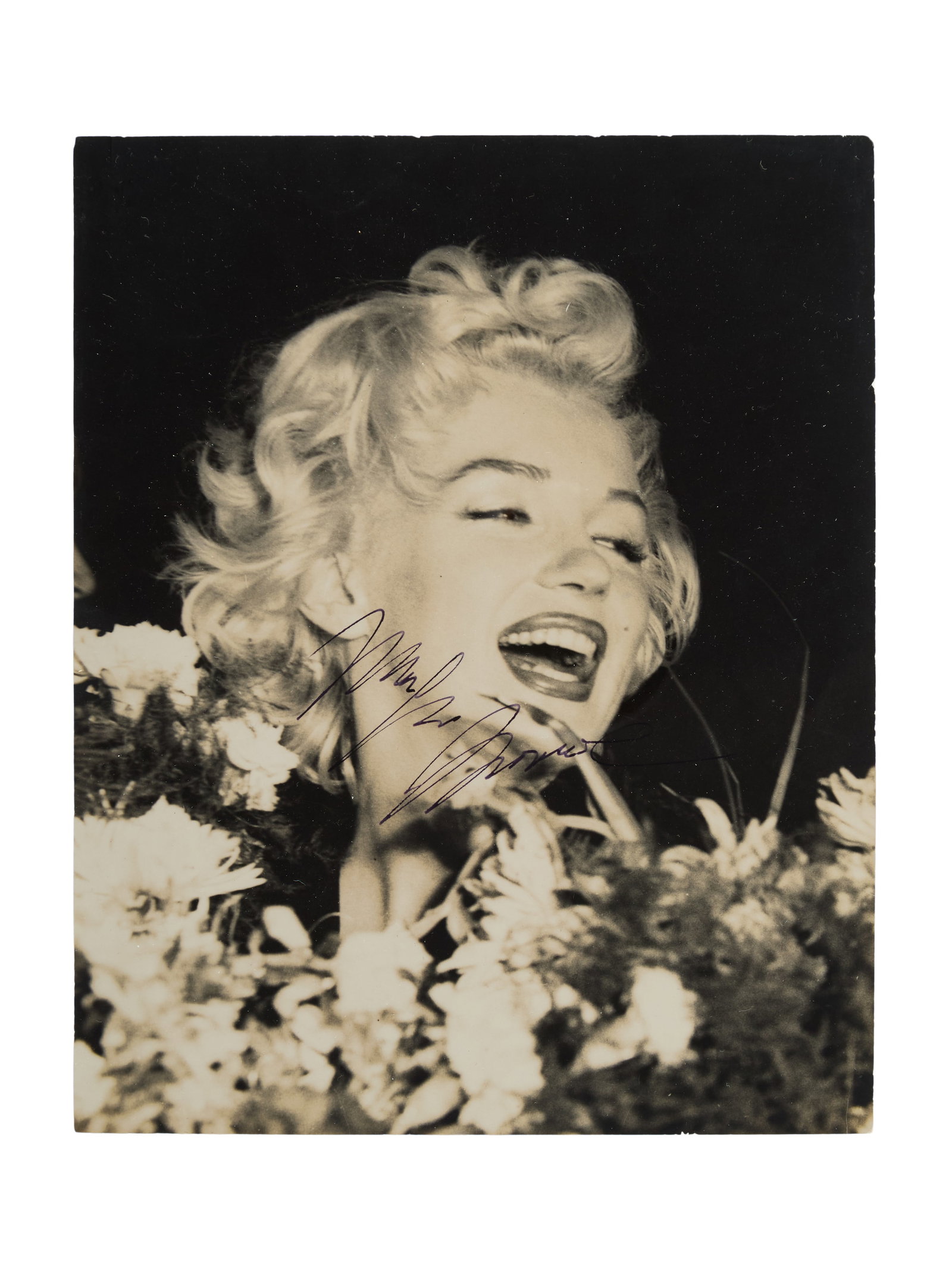 Marilyn Monroe | 1954 Signed Black and White Photograph: An original print; glossy finish, depicting the smiling star surrounded by flowers in Japan in February 1954 when she was on her "working" honeymoon with Joe DiMaggio; signed in black fountain pen ink