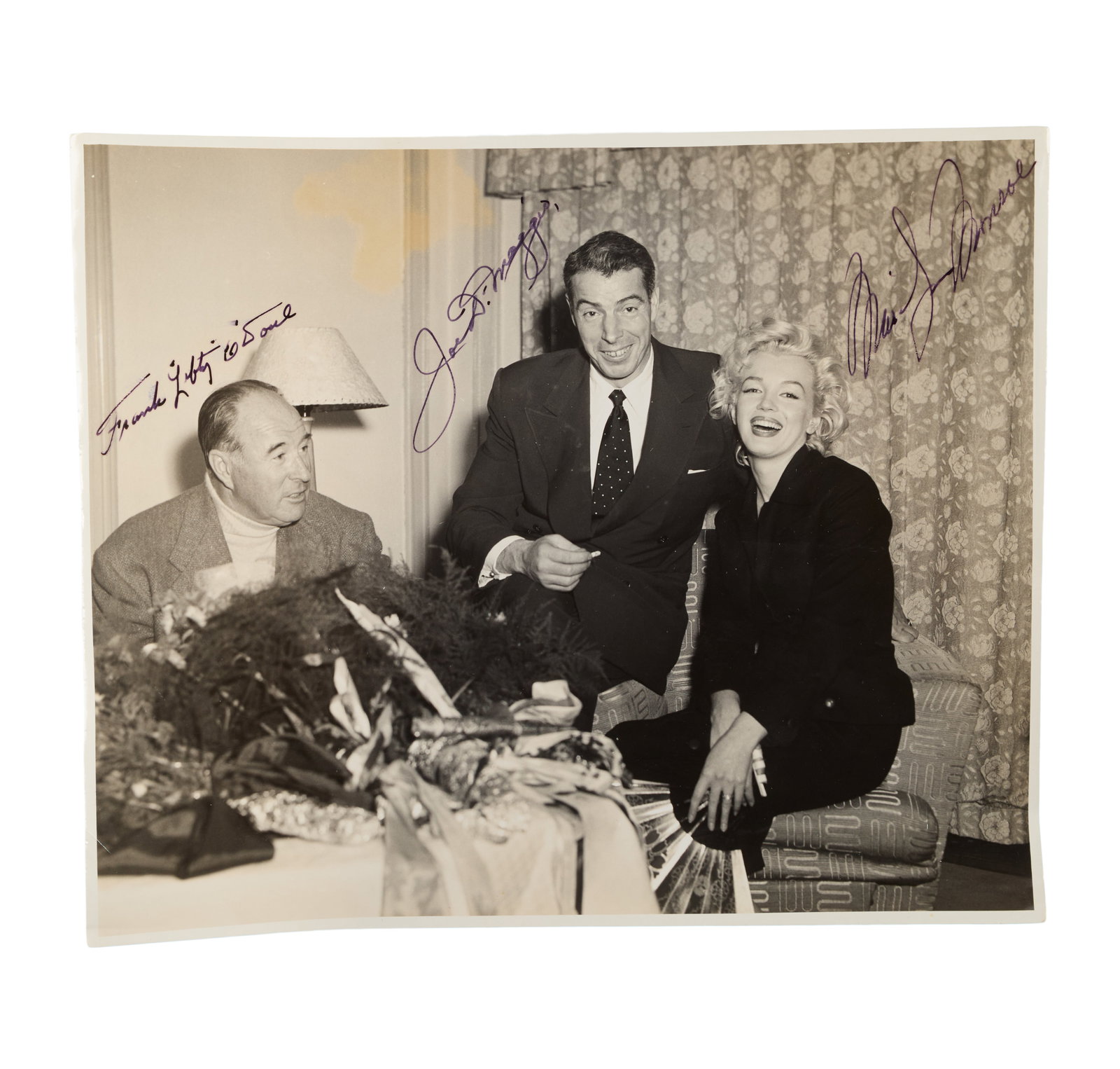 Marilyn Monroe and Joe DiMaggio, Et Al. | 1954 Signed Black and White Photograph: An original print; glossy finish, depicting the star, her then new husband Joe DiMaggio, and his buddy Lefty O'Doul sitting in a hotel room in Japan in February, 1954 when the couple was on their "wor