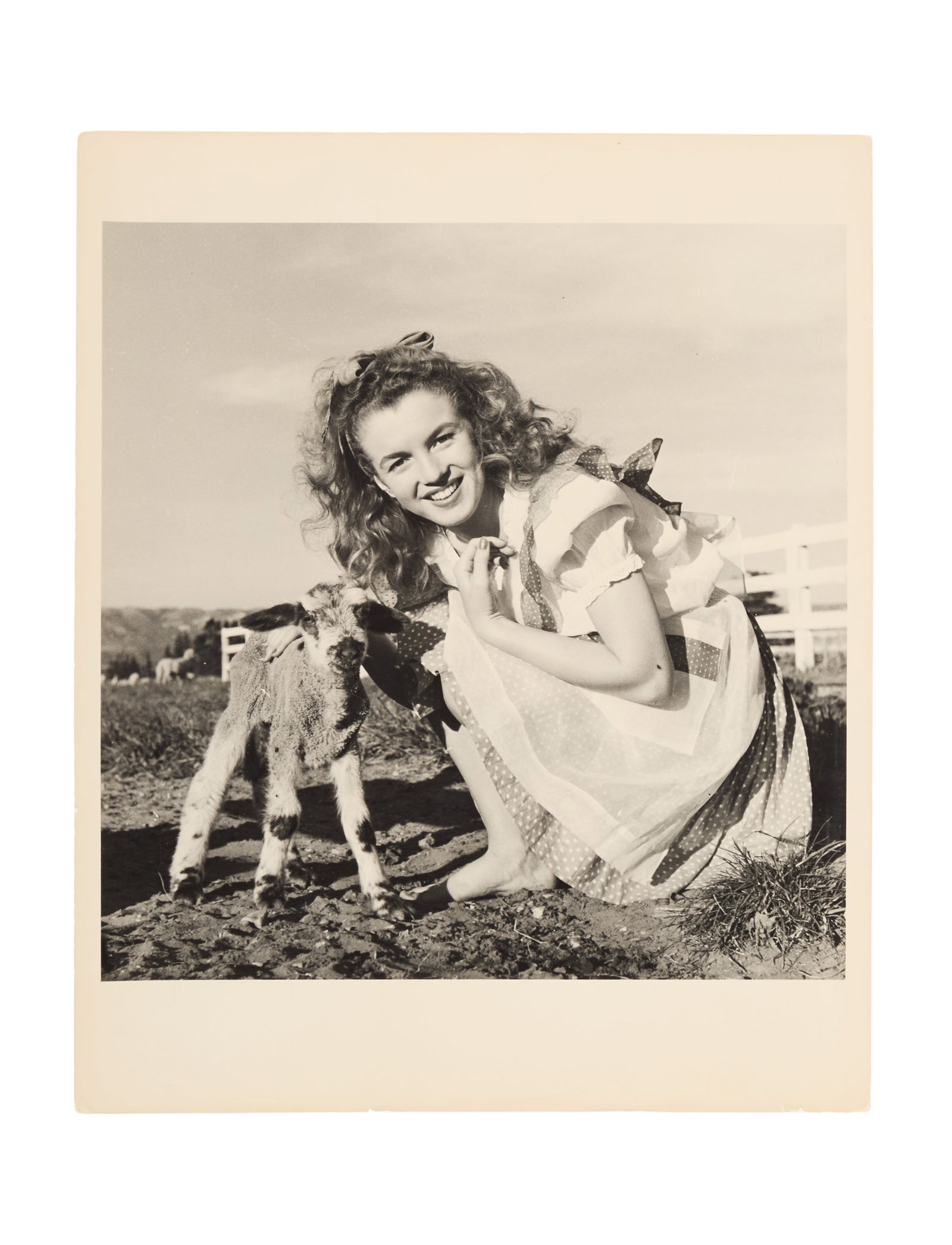 Marilyn Monroe | 1945/1970s Black and White Photograph by Andre De Dienes: A circa 1970s later print; semi-gloss finish, double-weight paper, depicting the then unknown 19 year-old beauty posing with a lamb; verso with a black ink credit stamp reading in part "Andre / Dienes
