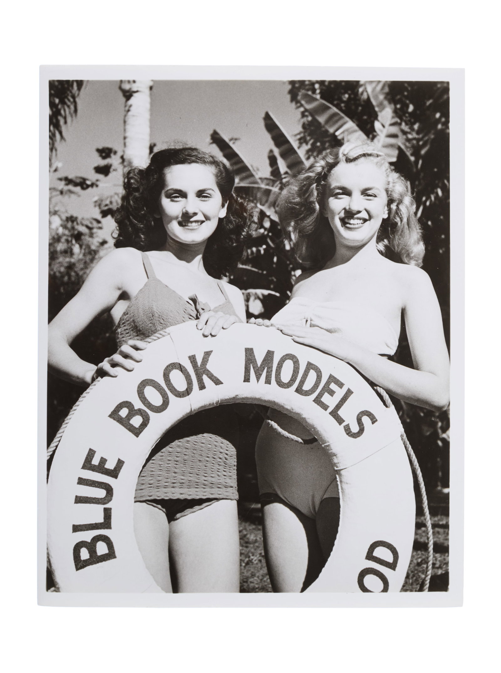 Marilyn Monroe | 1946/1987 Black and White Photograph by Joseph Jasgur: A 1987 later print; glossy finish, weight-and-a-half paper, depicting the blonde teenager (who was evidently still learning what her good angles were) standing next to a brunette as they both hold a l