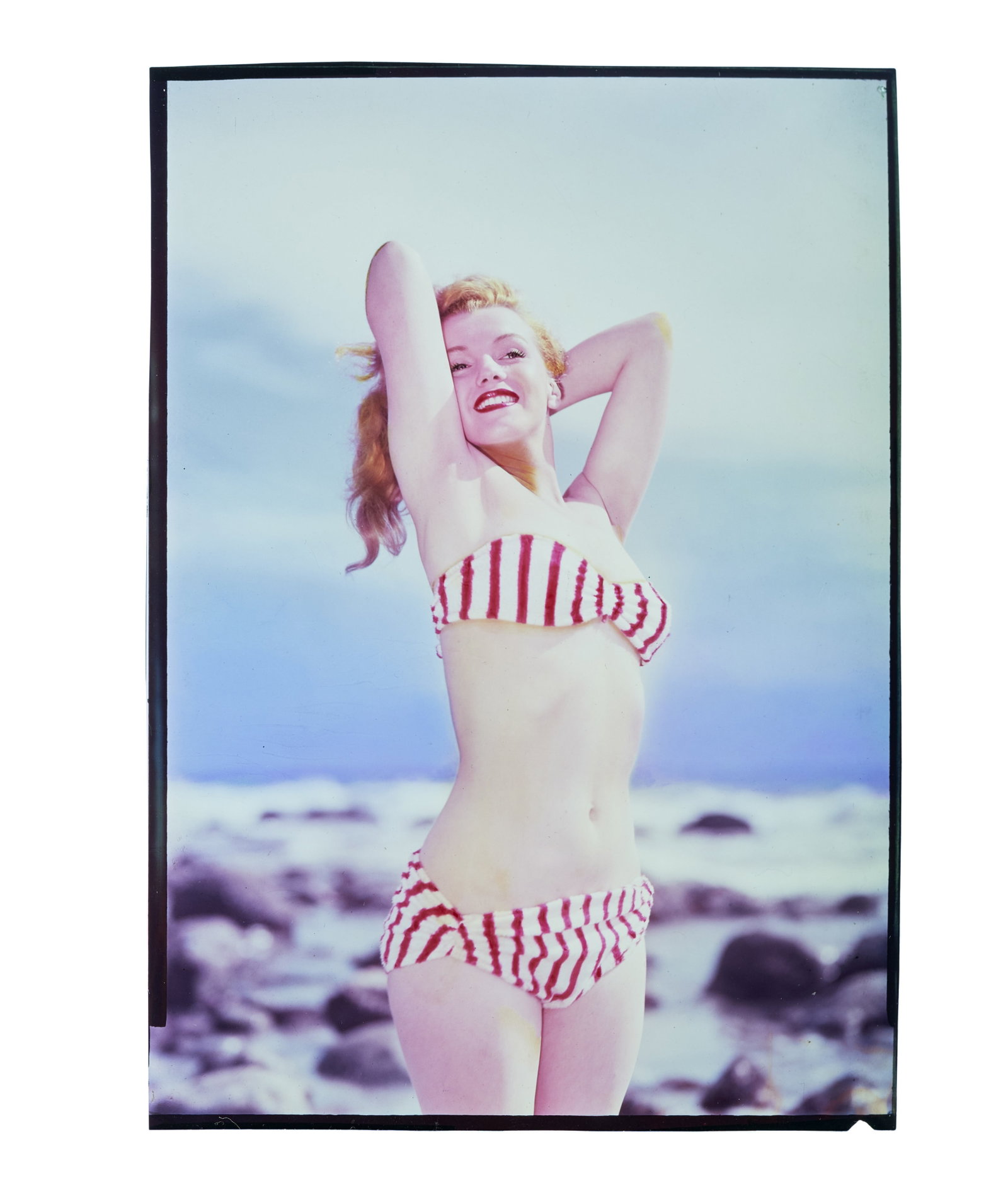 Marilyn Monroe | 1947/1960s Color Transparency by L?szl? Willinger: A later 1960s print; on film, depicting the then model looking totally vibrant, wearing a red and white striped bikini and matching red lipstick as she poses on the beach.