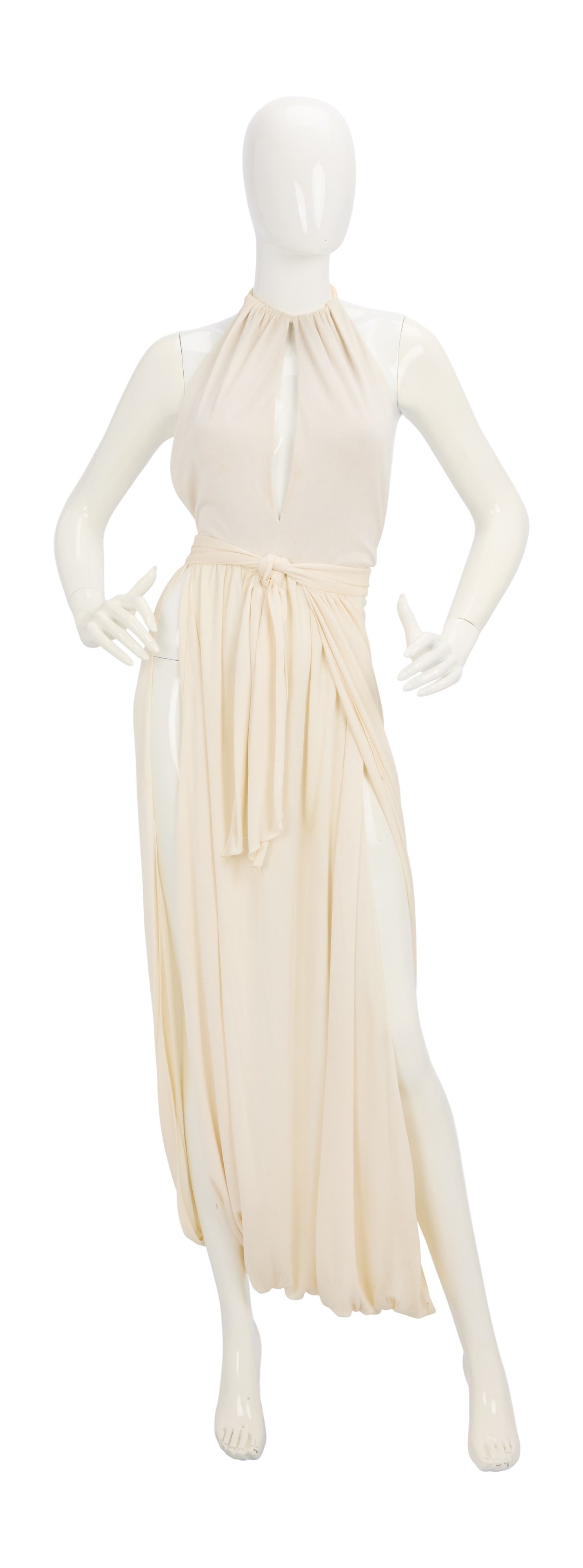 Ann-Margret | 1976 Dress by Bob Mackie Related to "The Last Remake of Beau Geste": A stunning halter-top style; made of off-white silk jersey, skirt portion wraps around from back in-between legs to create a harem look at hem, separate waist tie; label reads "Bob Mackie"; together w