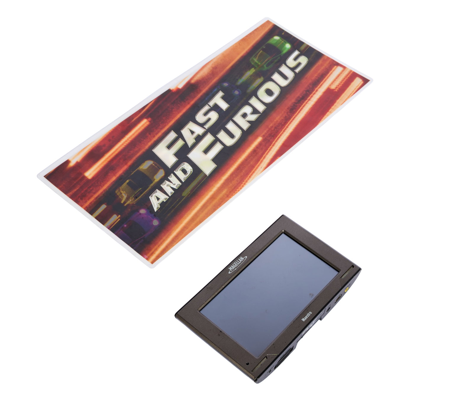 Fast & Furious | GPS Unit with Production Parking Card: A Magellan Maestro GPS unit from the production of Fast & Furious (Universal, 2009). Handwritten in silver-tone marker underneath the base of the unit is, "FAST 4." GPS units such as this can be seen