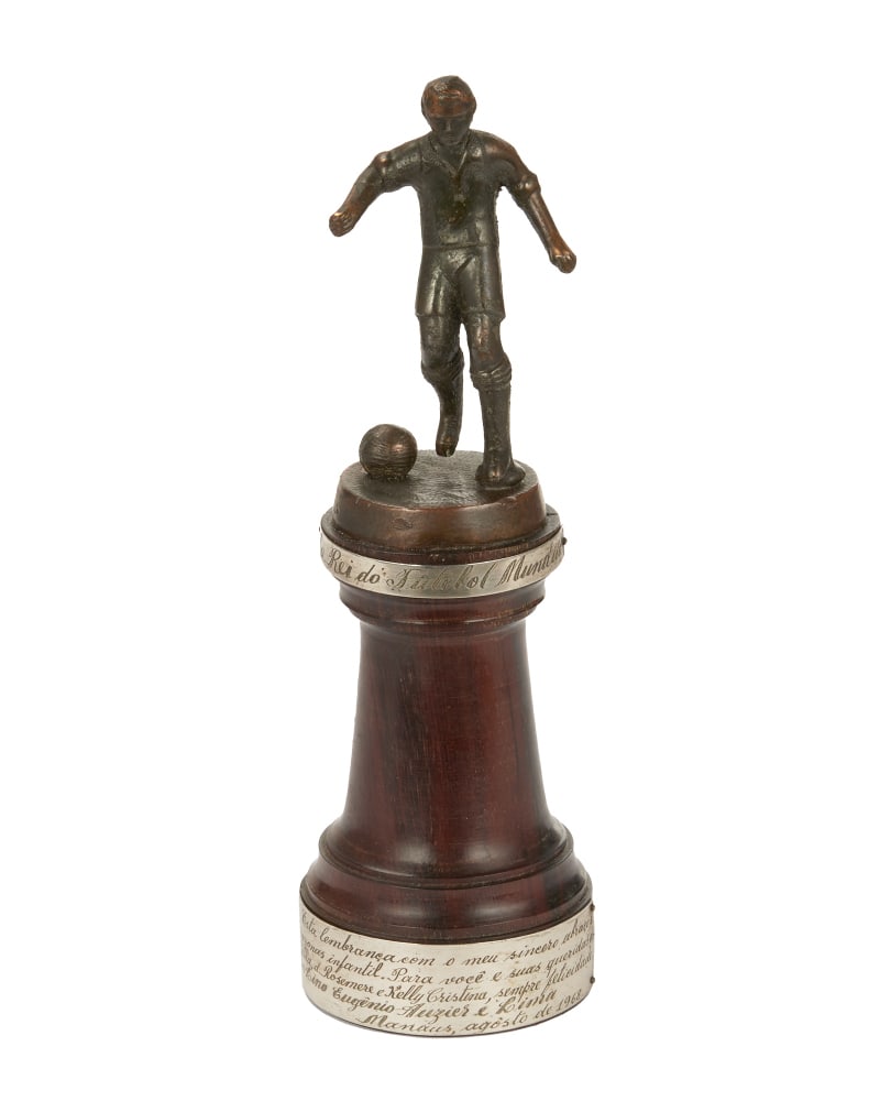 Pele | 1968 Manaus ?King of World Football? Tribute Trophy: A tribute trophy presented to Pele in August 1968 by Lino Eugenio Auzier e Lima, an official from the city of Manaus, Brazil. The first engraved plaque affixed to the top of the trophy reads, "Ao Rei
