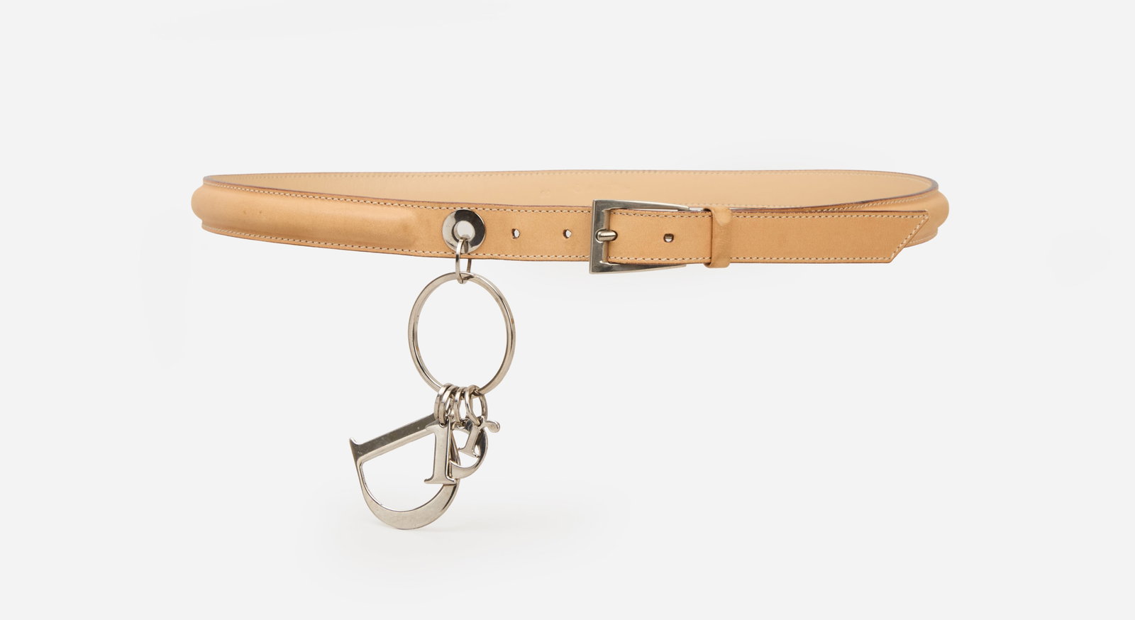 Christian Dior | Belt with Charm: Christian Dior beige belt. The slim belt features tonal edge stitching, brown edges, and a silver-tone buckle. The design is accented by a hanging silver-tone charm ring suspending the iconic "Dior" l