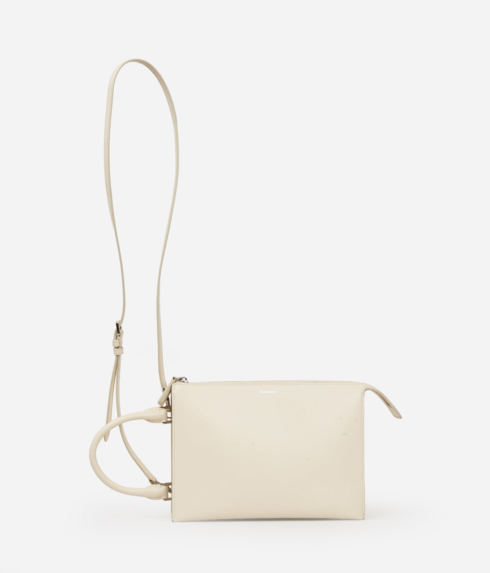 Jil Sander | Tootie Leather Handbag: Jil Sander Tootie leather handbag. The rectangular white handbag features a circular top handle and a detachable shoulder strap. The front is embossed with the Jil Sander logo. A silver-tone center