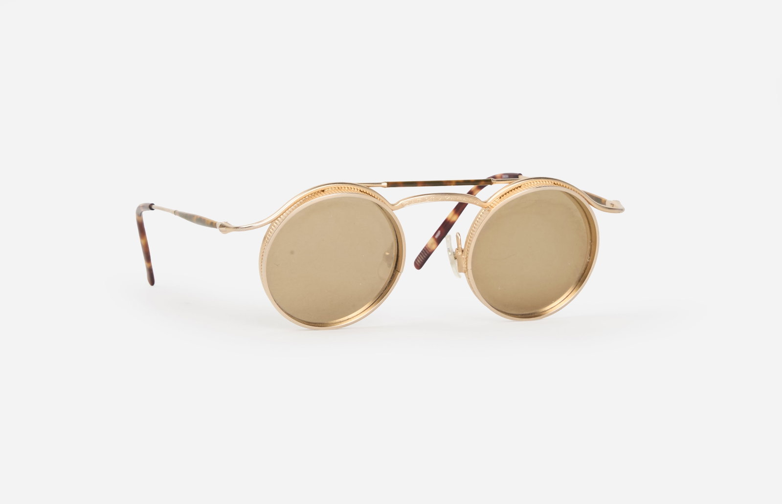 Matsuda | Sunglasses: Matsuda gold-tone sunglasses. These sunglasses feature round, dark, green-tinted lenses set in thin gold-tone metal frames, with adjustable clear nose pads and slim metal temples finished with dark