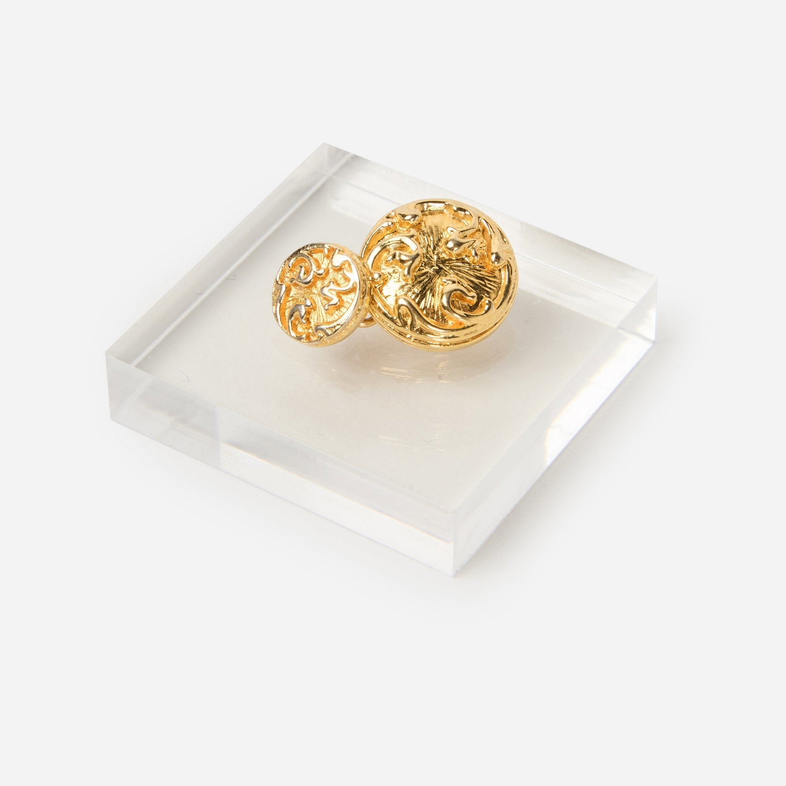 Chanel | Single Cuff Link: Chanel single cuff link designed as a double link, the gold-tone circular plaques joined by a link chain, 1 inch overall. Marked "Chanel". Coco Chanel revolutionized jewelry by combining fine gems wit