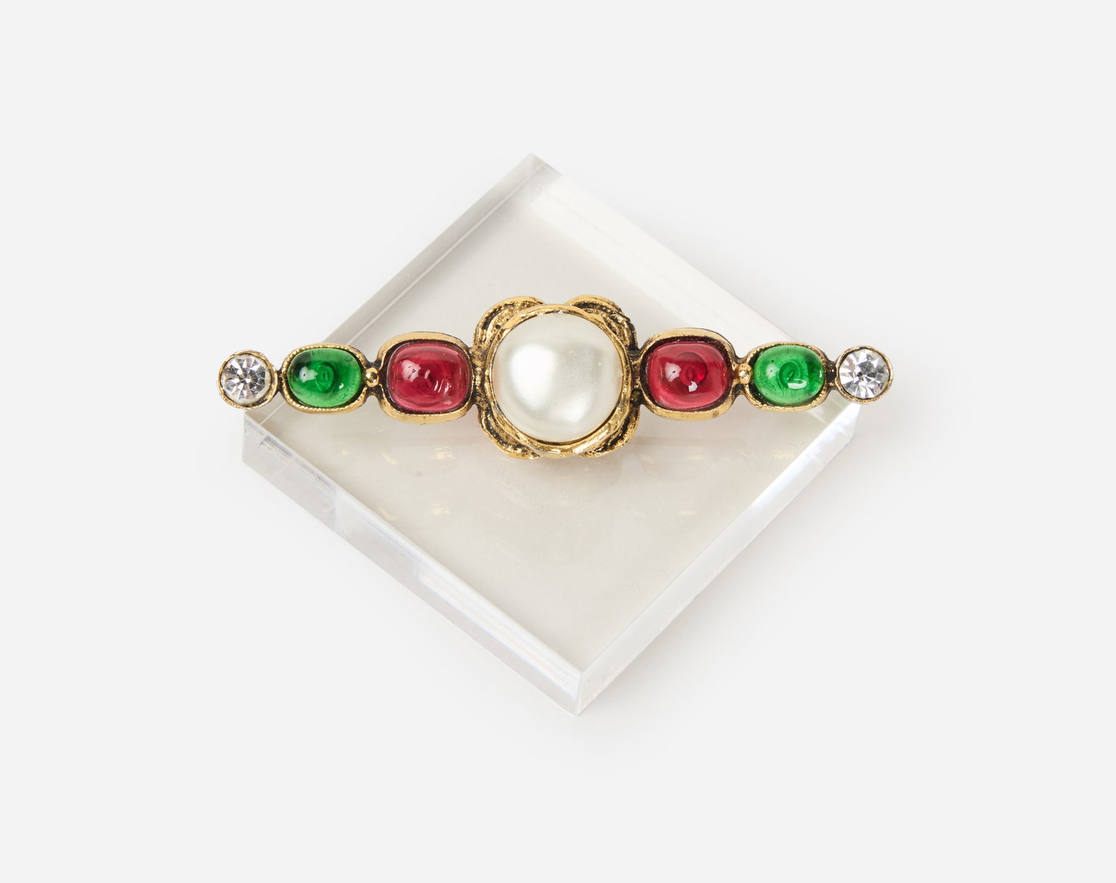 Chanel | 1985 Gripoux Bar Brooch: Chanel Gripoux Bar Brooch designed as a gold tone bar brooch, accented by a central simulated pearl, green and red glass and rhinestone accents, dated 1985. Measures 3 inches. Coco Chanel