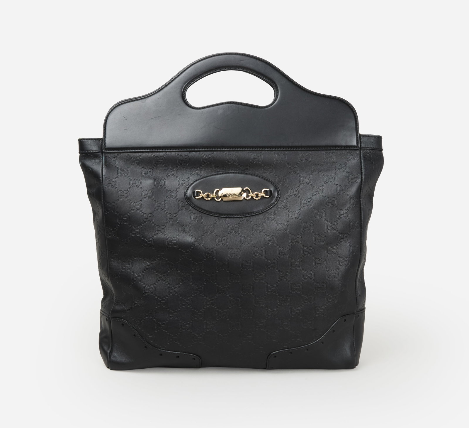 Gucci | Guccissima Monogram Punch Leather Tote: Gucci Guccissima monogram punch leather tote bag. Black leather tote bag featuring an allover embossed Gucci GG monogram pattern. The structured design features an integrated cutout top handle and a s