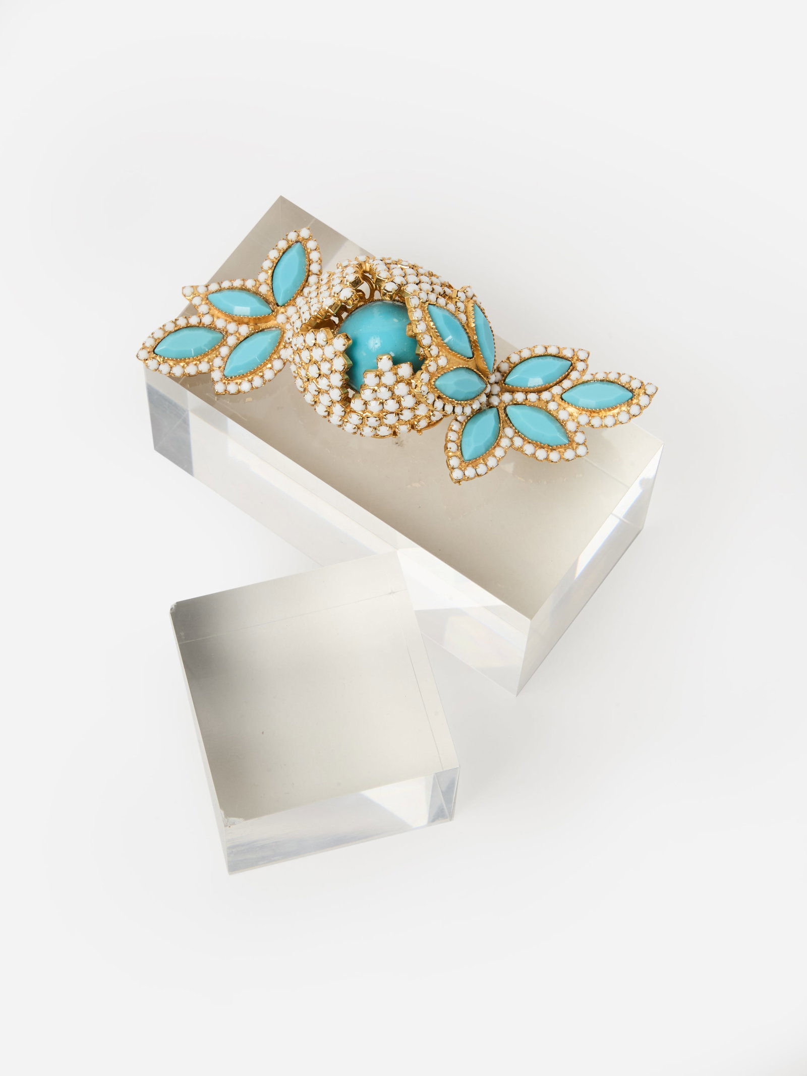 William DeLillo | Floral Brooch: William DeLillo floral brooch. Designed as a gold-tone floral brooch, set with white rhinestones and simulated turquoise. Measuring 1 1/2 x 4 1/2 inches. Marked "Wm deLillo." William de Lillo was a