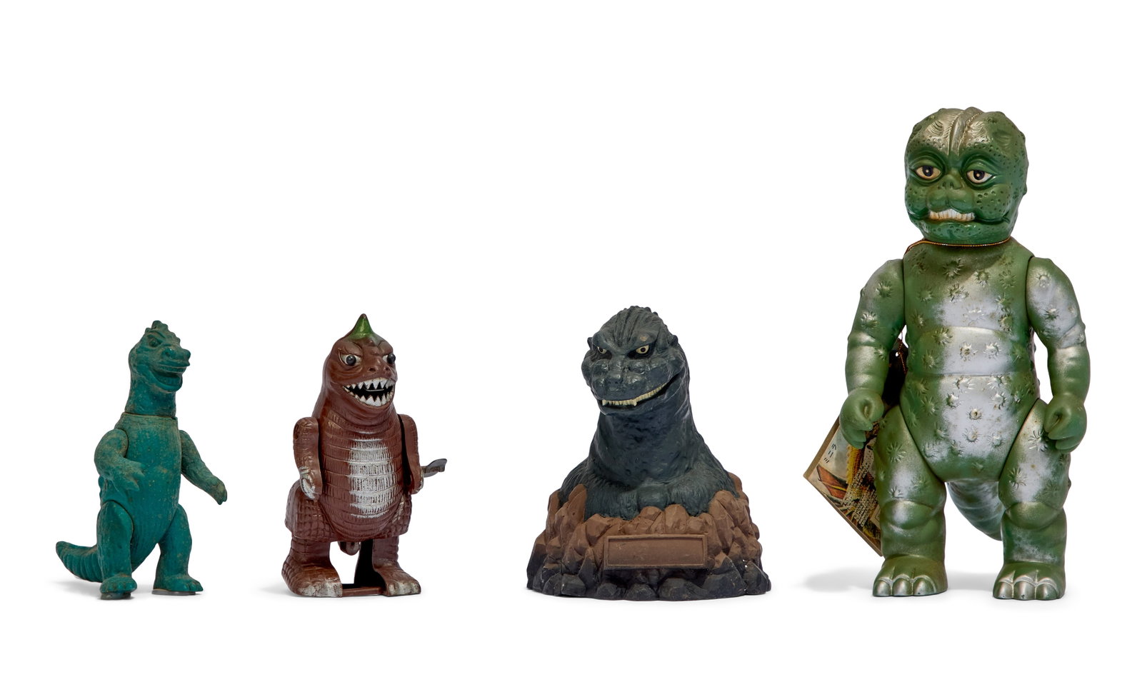 Godzilla | Vintage Figures (4): A collection of four vintage figures of characters from various installments of the Godzilla franchise. Includes a 1992 Minilla sofubi figure with Bandai tag (Bullmark), 1998 Godzilla BustBank coin ba