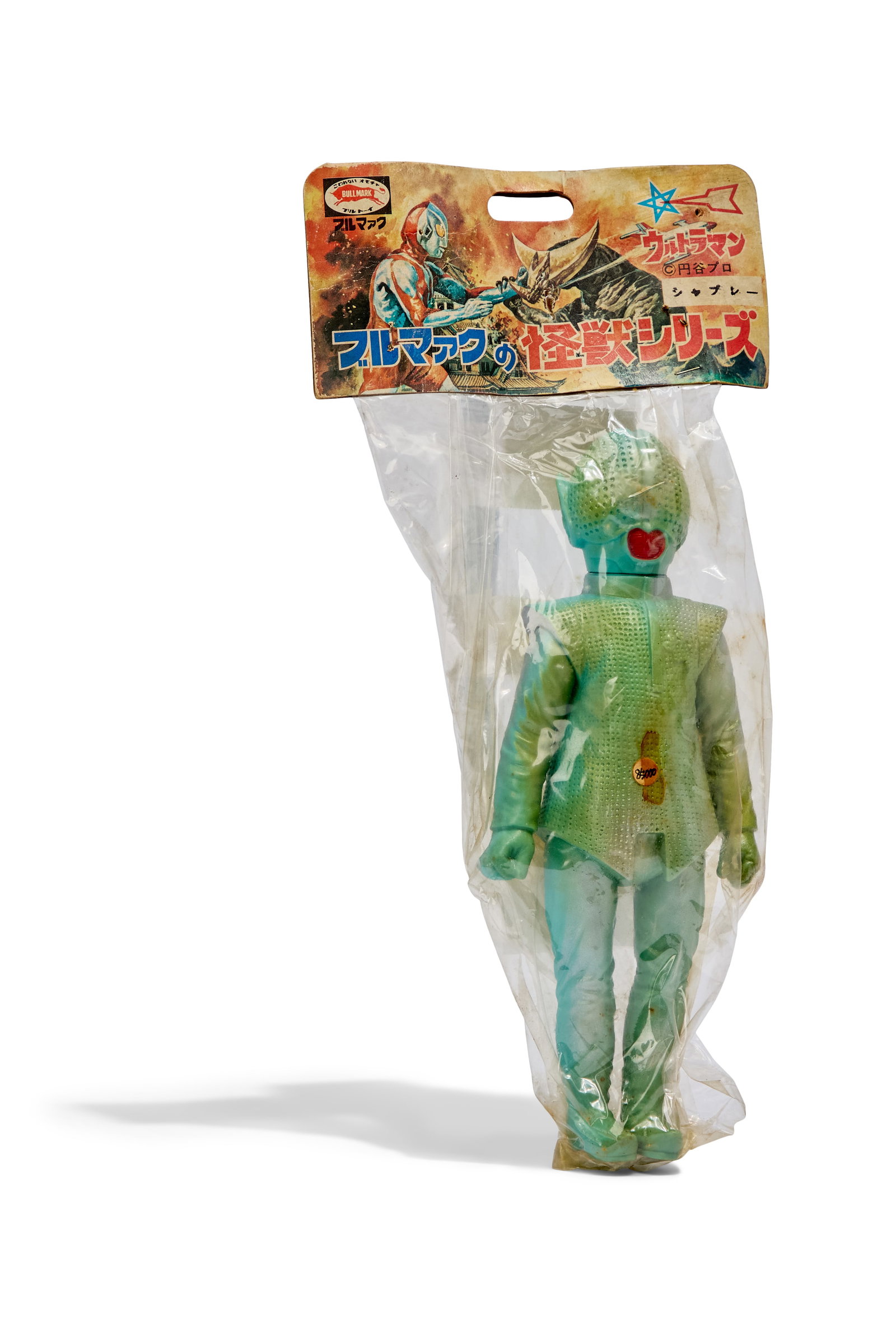 Sofubi | Vintage Ultraseven Seijin Shapley Alien Figure with Original Packaging: A vintage Bullmark Ultraseven Seijin Shapley Alien figure with its original packaging, including header and plastic. Minor damage present to the header and the plastic contains an additional staple