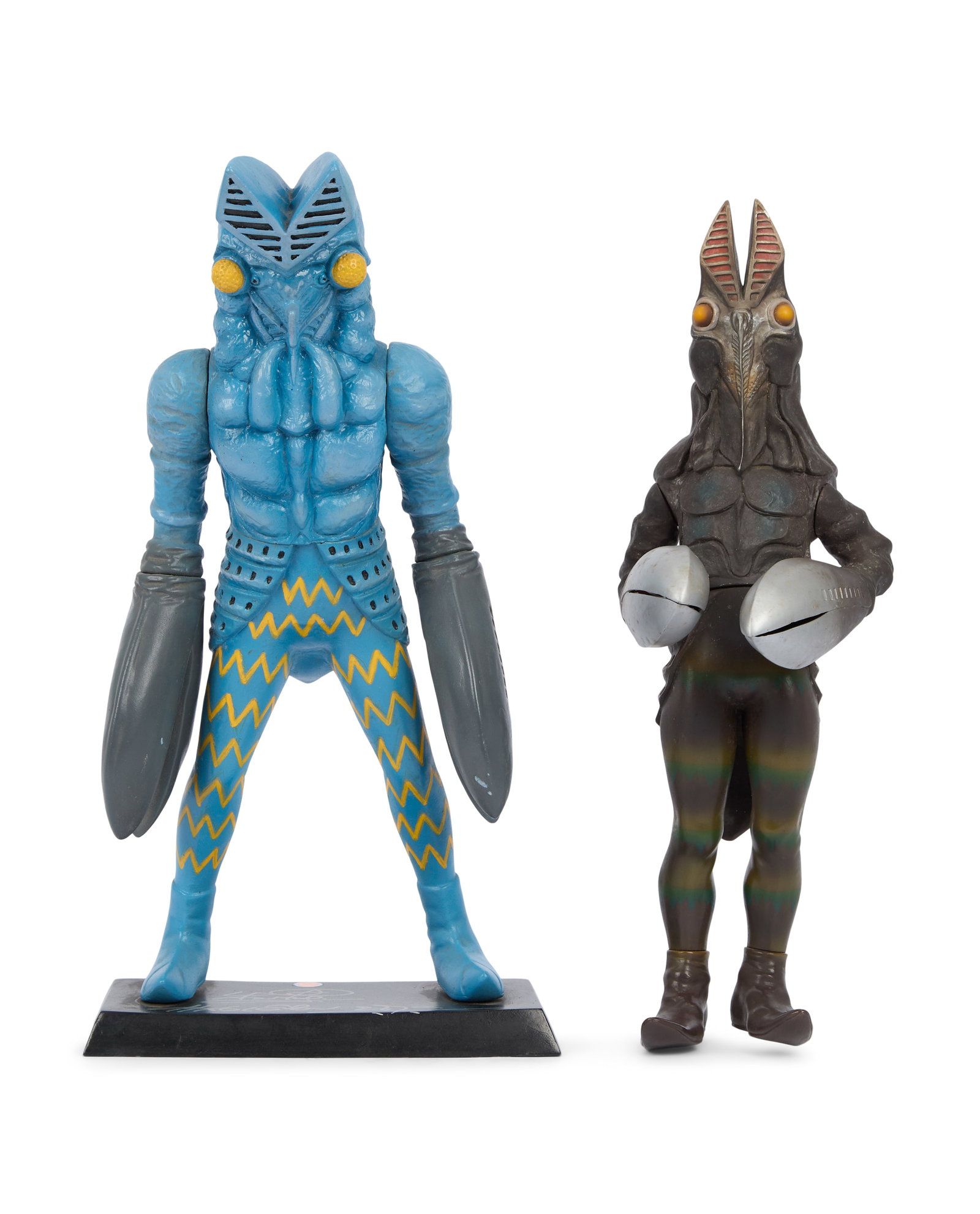 Ultraman | Alien Baltan Figurine Signed by Sompote Sands with Additional Figurine: A sofubi Alien Baltan figurine mounted to a black stand. The stand features the signature of filmmaker Sompote Sands in silver-tone marker. Together with an additional Alien Baltan sofubi figure.