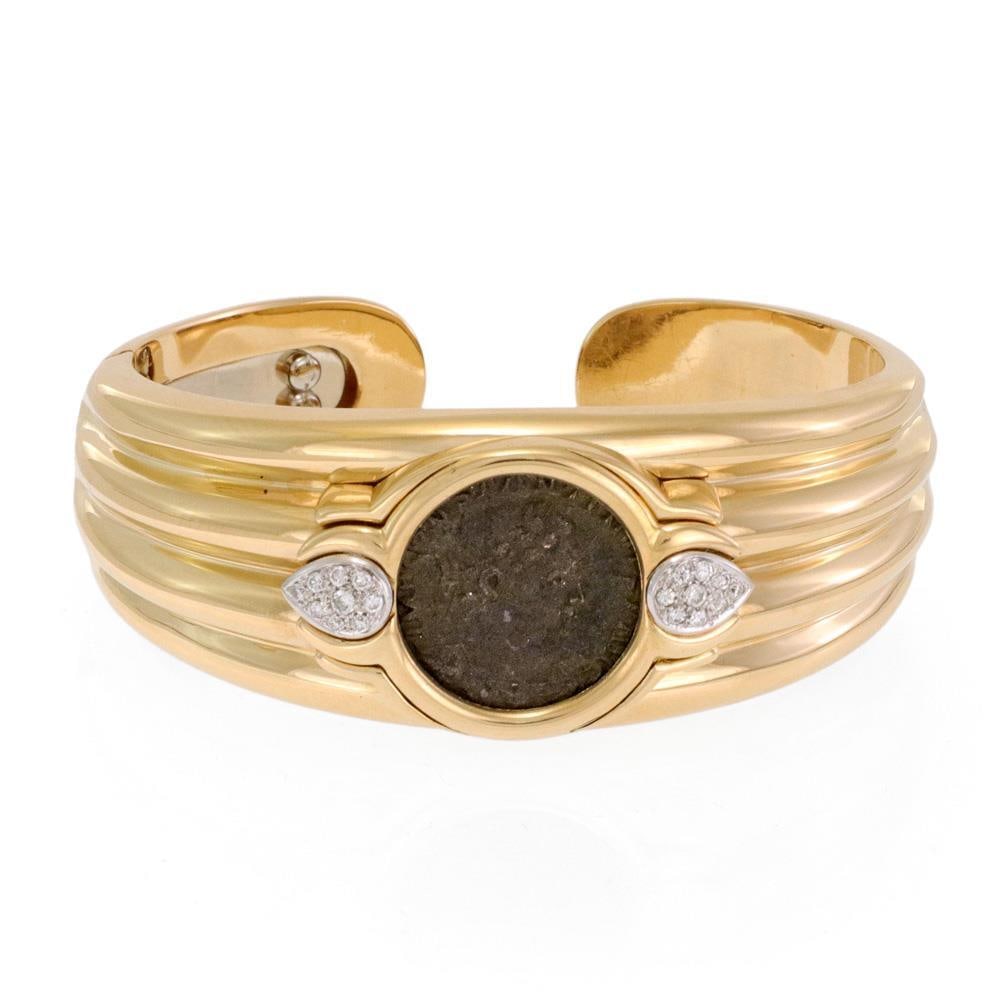 Elegant 18k Gold Cuff Bracelet with Roman Bronze Coin and Diamonds: Elegant 18k Gold Cuff Bracelet with Roman Bronze Coin and Diamonds This stunning estate bracelet showcases exquisite craftsmanship, made from 18k yellow gold with white gold accents. The polished cuff