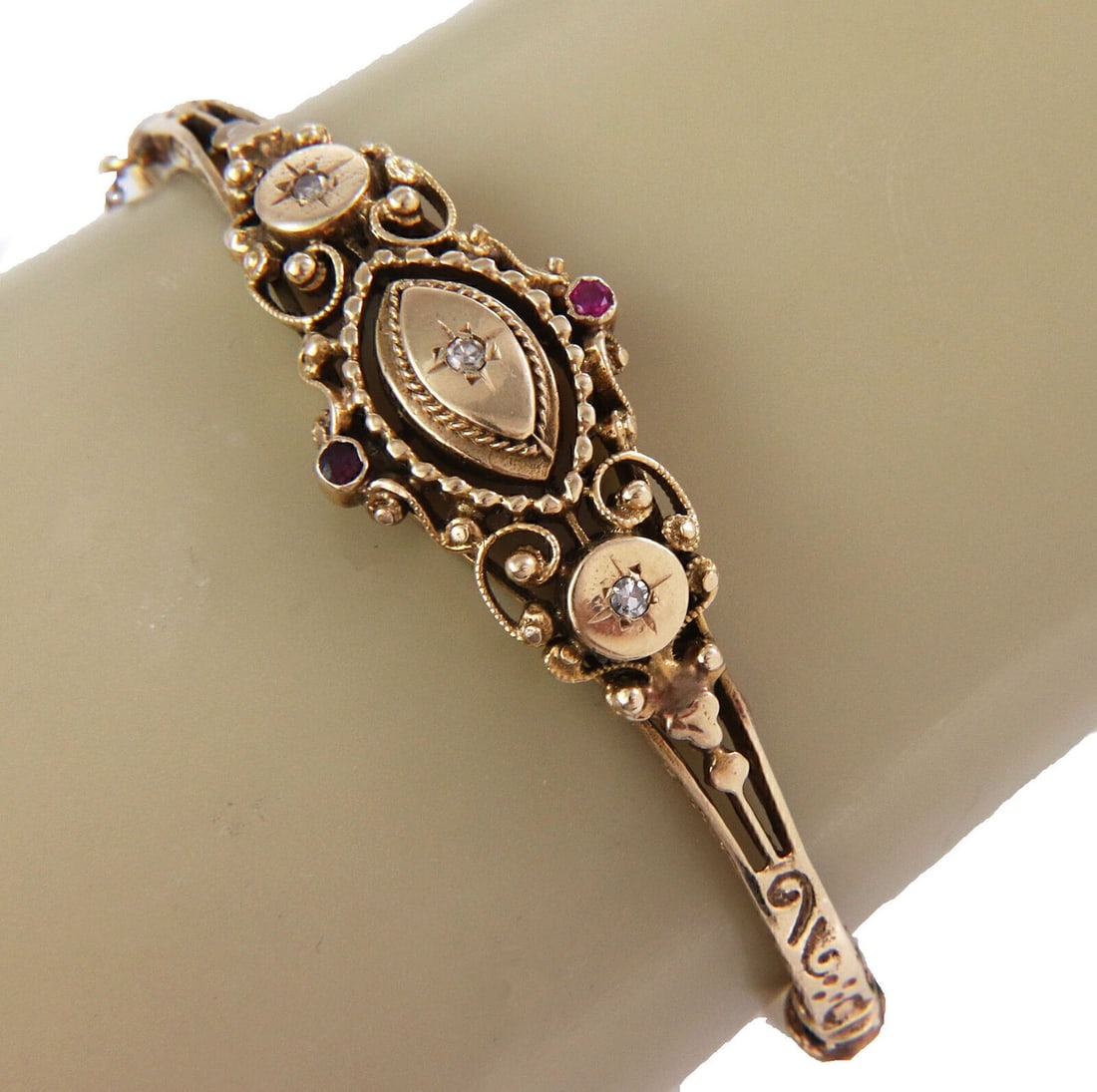 Vintage 14k Yellow Gold Diamond Ruby Floral Scroll Bangle: Vintage 14k Yellow Gold Diamond Ruby Floral Scroll Bangle Indulge in the elegance of this exquisite 14k Yellow Gold Bangle, featuring a stunning arrangement of diamonds and rubies. The sophisticated d