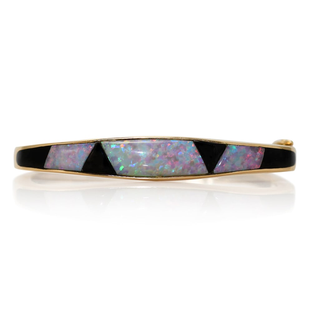 14K Yellow Gold Bangle Bracelet with Synthetic Opal and Onyx: 14K Yellow Gold Bangle Bracelet with Synthetic Opal and Onyx This stunning 14K yellow gold bangle bracelet features a beautiful combination of synthetic opal and black onyx. Crafted in a classic bangl