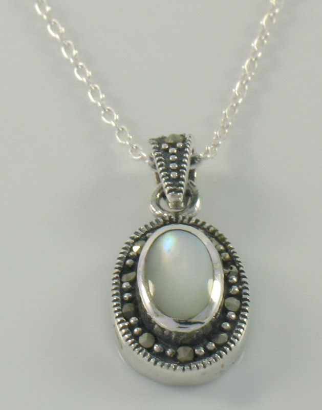 Marcasite Sterling Silver Mother of Pearl Pendant with Chain: Marcasite Sterling Silver Mother of Pearl Pendant with Chain This exquisite pendant showcases a stunning oval bezel set Mother of Pearl stone, beautifully framed by intricate marcasite accents. Crafte