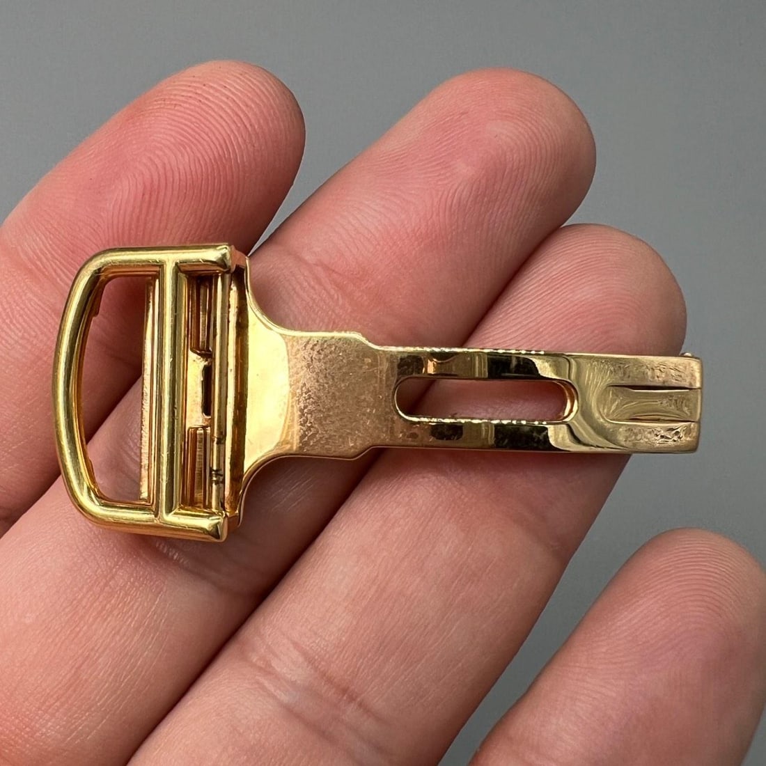 18K Yellow Gold Deployant Buckle for 18mm Strap by Cartier: 18K Yellow Gold Deployant Buckle for 18mm Strap by Cartier This is a Cartier deployant buckle crafted from 18K yellow gold. It weighs 13.4 grams and is designed to fit an 18mm strap. The buckle is pre