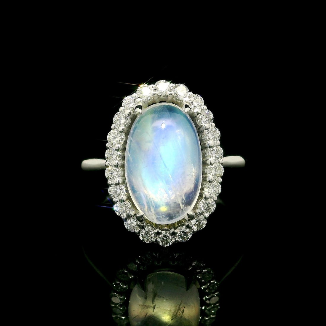 Custom 14k White Gold 4.31ctw Moonstone Diamond Halo Ring: Custom 14k White Gold 4.31ctw Moonstone Diamond Halo Ring This exquisite cocktail ring features a stunning elongated oval moonstone at its center, measuring 12.6x8mm and weighing 3.78ct. The moonstone
