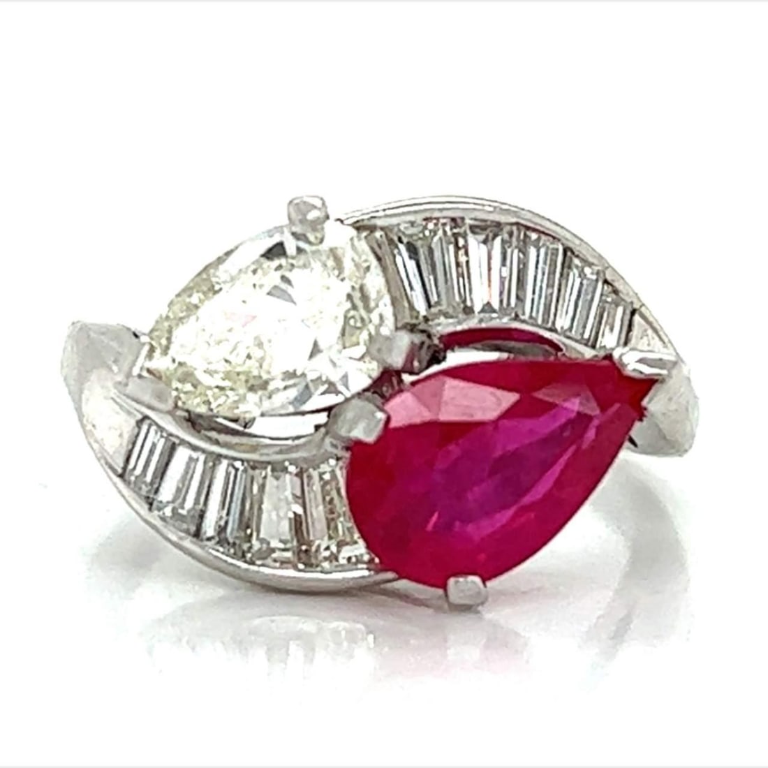 Platinum Ruby Ring with 1.50 Ct Diamond & 10 Baguettes: Platinum Ruby Ring with 1.50 Ct Diamond & 10 Baguettes This exquisite Platinum Diamond & Ruby Ring features a stunning 2.25 Ct. ruby at its center, complemented by a pear-shaped diamond weighing appro