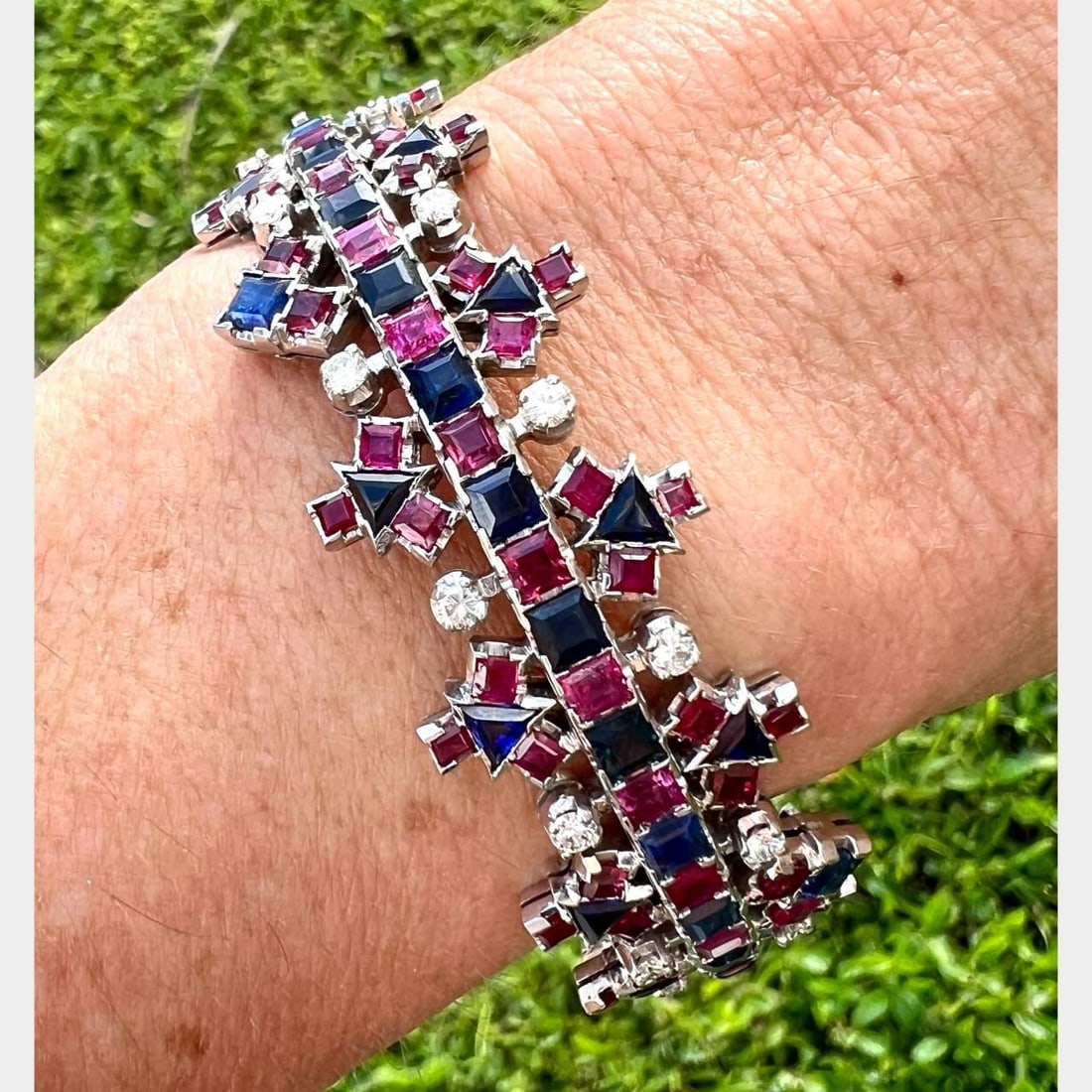 1960's 18K White Gold Diamond Ruby Sapphire Bangle Bracelet: 1960's 18K White Gold Diamond Ruby Sapphire Bangle Bracelet This stunning 1960's bangle bracelet is crafted from 18K white gold and features an exquisite arrangement of gemstones. It is adorned with 2