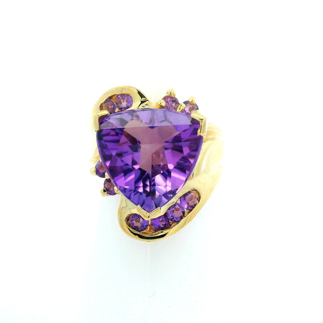 10k Yellow Gold Amethyst Cocktail Ring Trillion Rolltop Design: 10k Yellow Gold Amethyst Cocktail Ring Trillion Rolltop Design This exquisite Estate cocktail ring features a stunning trillion-cut natural amethyst at its center, measuring approximately 12.4 x 13.3m