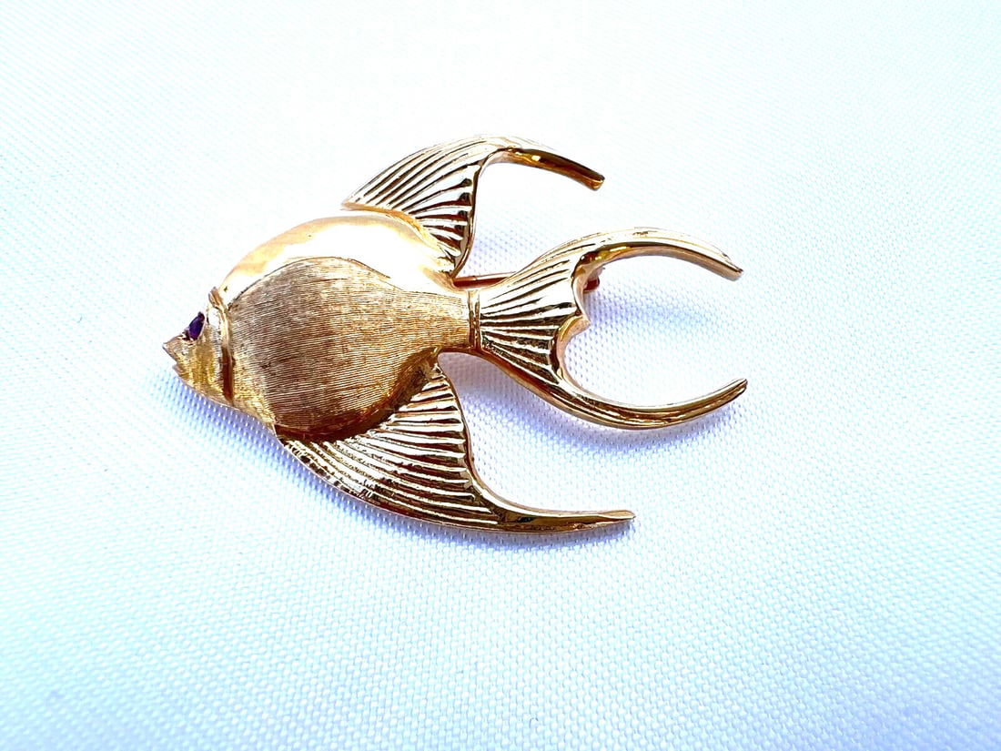 CMG 14K Yellow Gold Fish Brooch with Red Stone: CMG 14K Yellow Gold Fish Brooch with Red Stone This exquisite 14K yellow gold brooch features a beautifully crafted fish design adorned with a striking red stone. The brooch is fully signed and
