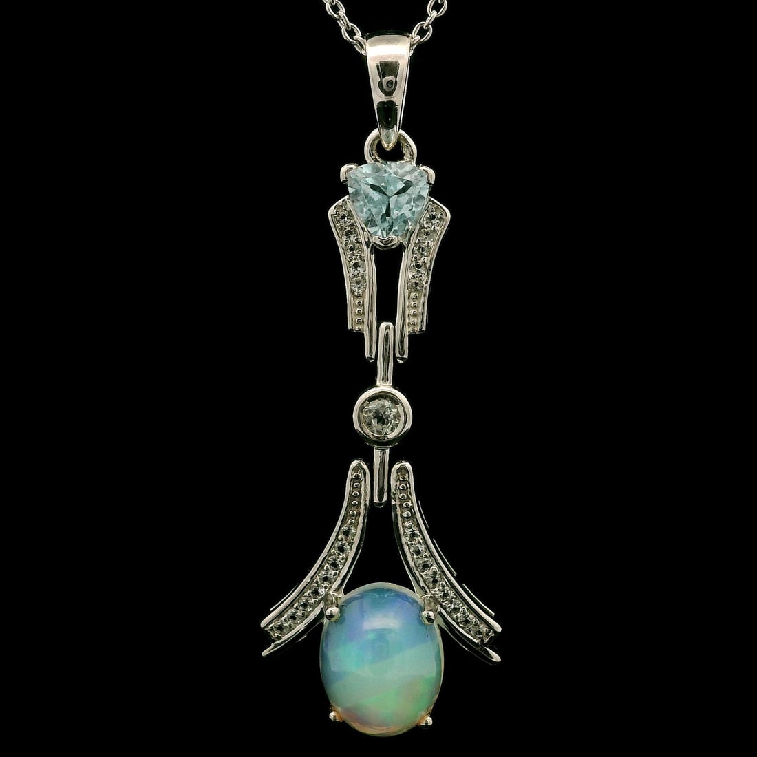 Sterling Silver Ethiopian Opal Pendant Necklace with Blue Topaz Accents: Sterling Silver Ethiopian Opal Pendant Necklace with Blue Topaz Accents This stunning flared pendant necklace features a captivating Ethiopian Opal at its center, showcasing a beautiful blend of blue