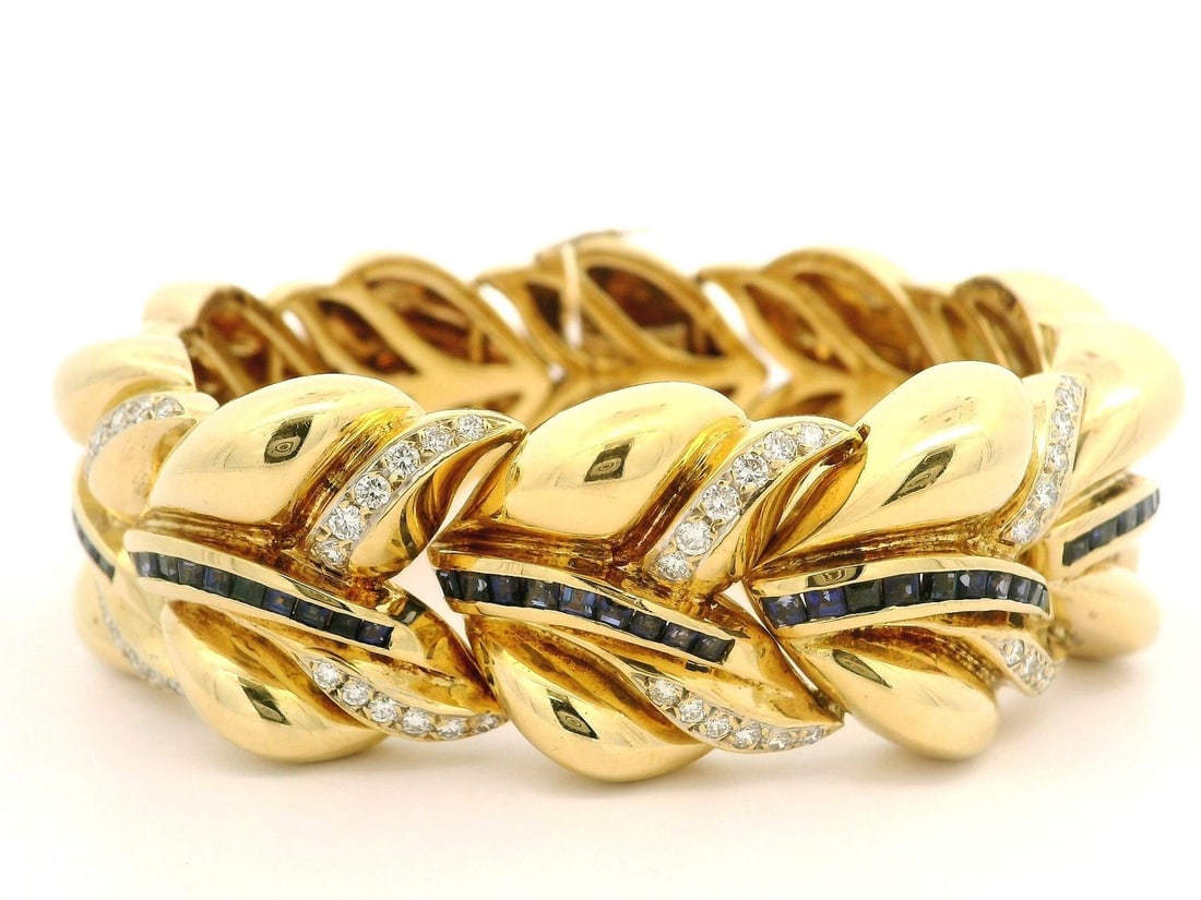 18k Yellow Gold Wide Cuff Bracelet with Sapphire and Diamond: 18k Yellow Gold Wide Cuff Bracelet with Sapphire and Diamond This stunning cuff bracelet is crafted from solid 18k yellow gold and showcases a bold design with a wide puffed leaf shape. Adorned with a