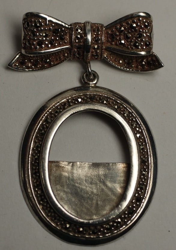 Handcrafted Antique Pendant in Sterling Silver with Marcasite Bow and Oval Motif: Handcrafted Antique Pendant in Sterling Silver with Marcasite Bow and Oval Motif This antique pendant features a bow and oval design crafted in sterling silver with marcasite accents. The piece is han