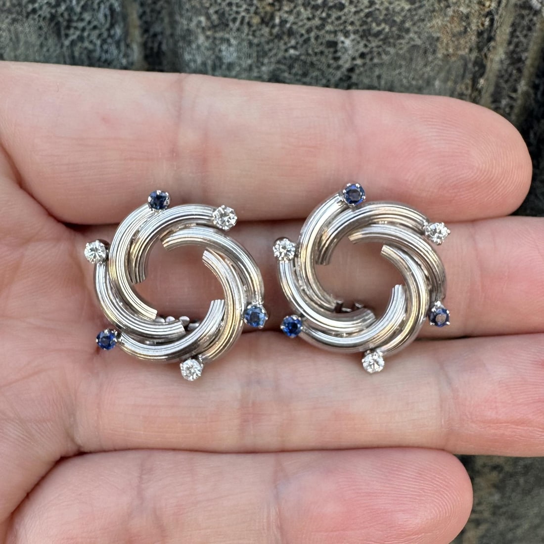 18k White Gold Vintage Earrings With Sapphire and Diamond Accents: 18k White Gold Vintage Earrings With Sapphire and Diamond Accents These vintage earrings feature an elegant grooved swirl infinity design crafted in solid 18k white gold. Each stud earring is set with